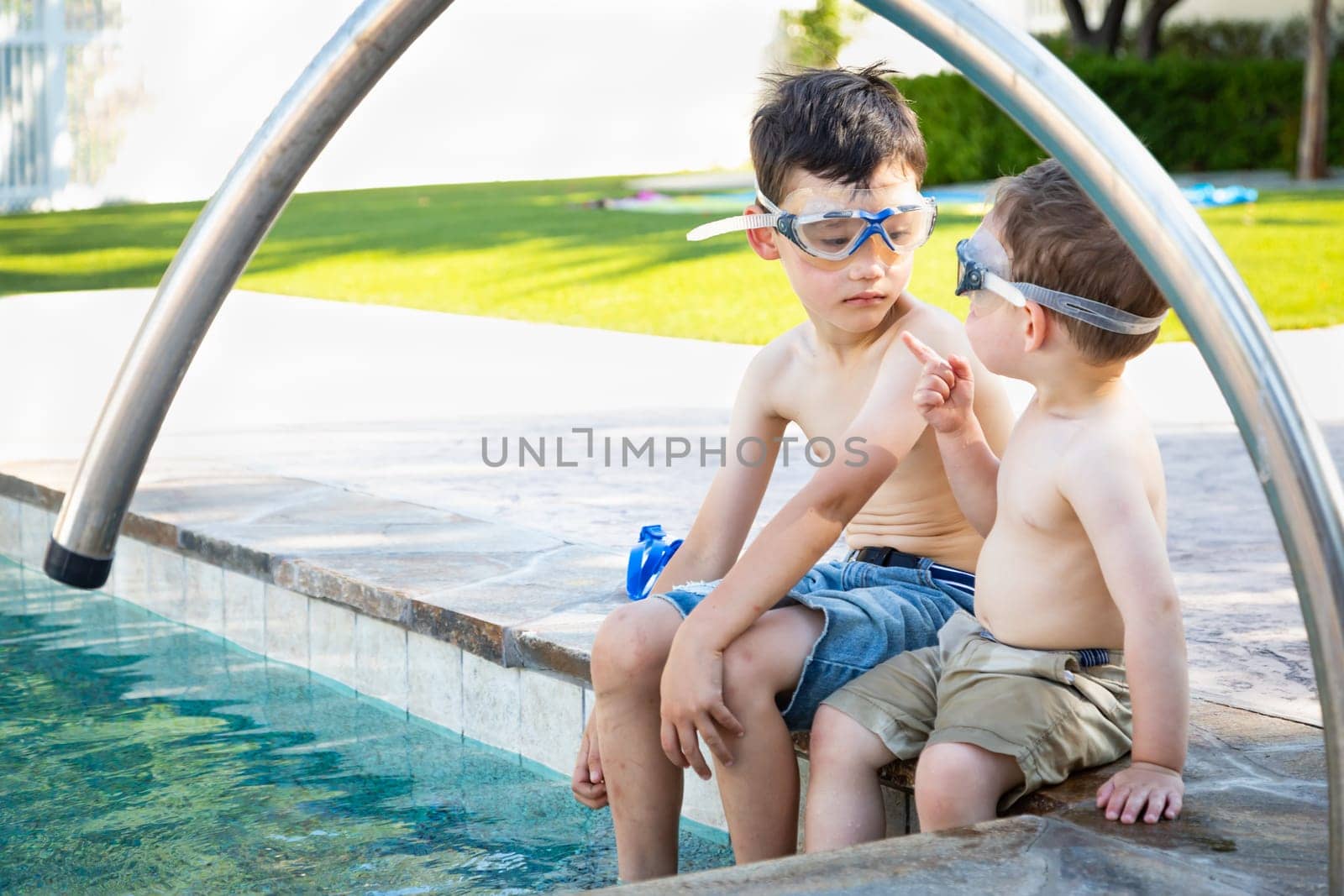 Young Mixed Race Chinese and Caucasian Brothers Wearing Swimming Goggles Playing At The Pool