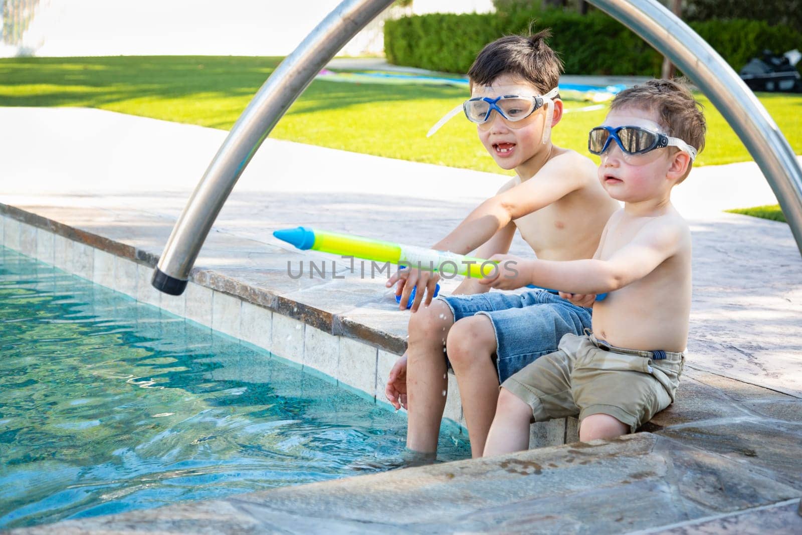 Young Mixed Race Chinese and Caucasian Brothers Wearing Swimming Goggles Playing At The Pool