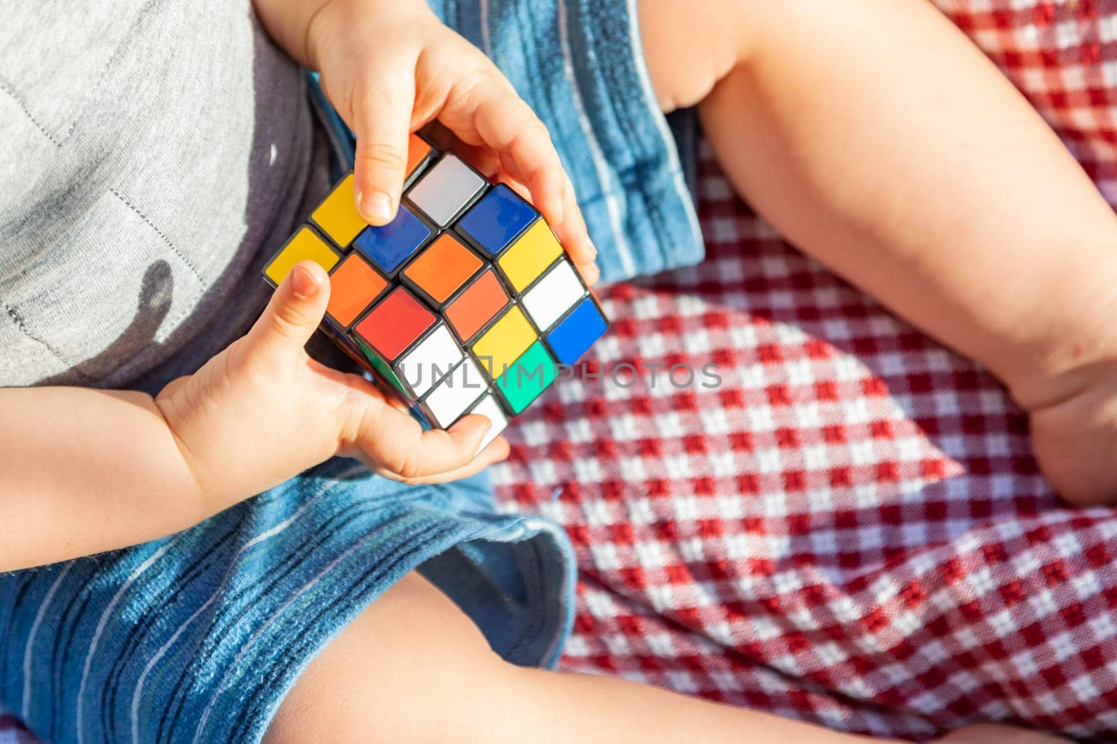 Baby Boy Sitting on Picnic Blanket Playing With Cube Puzzle