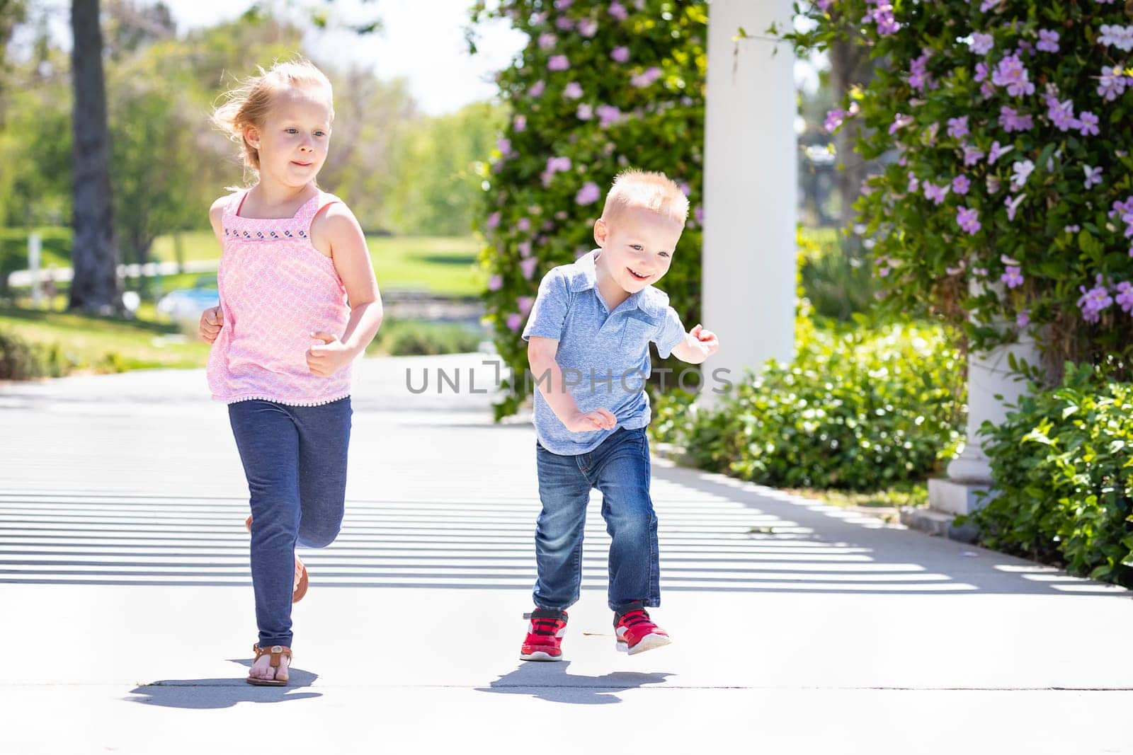 Young Sister and Brother Having Fun Running At The Park.
