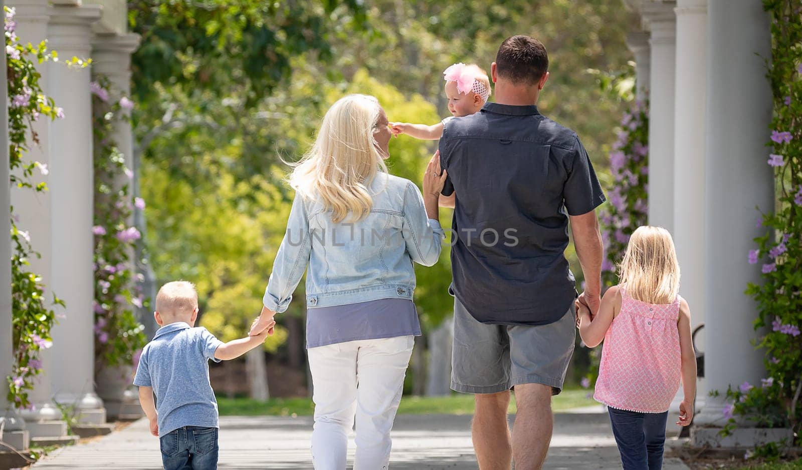 Young Caucasian Family Taking A Walk In The Park.