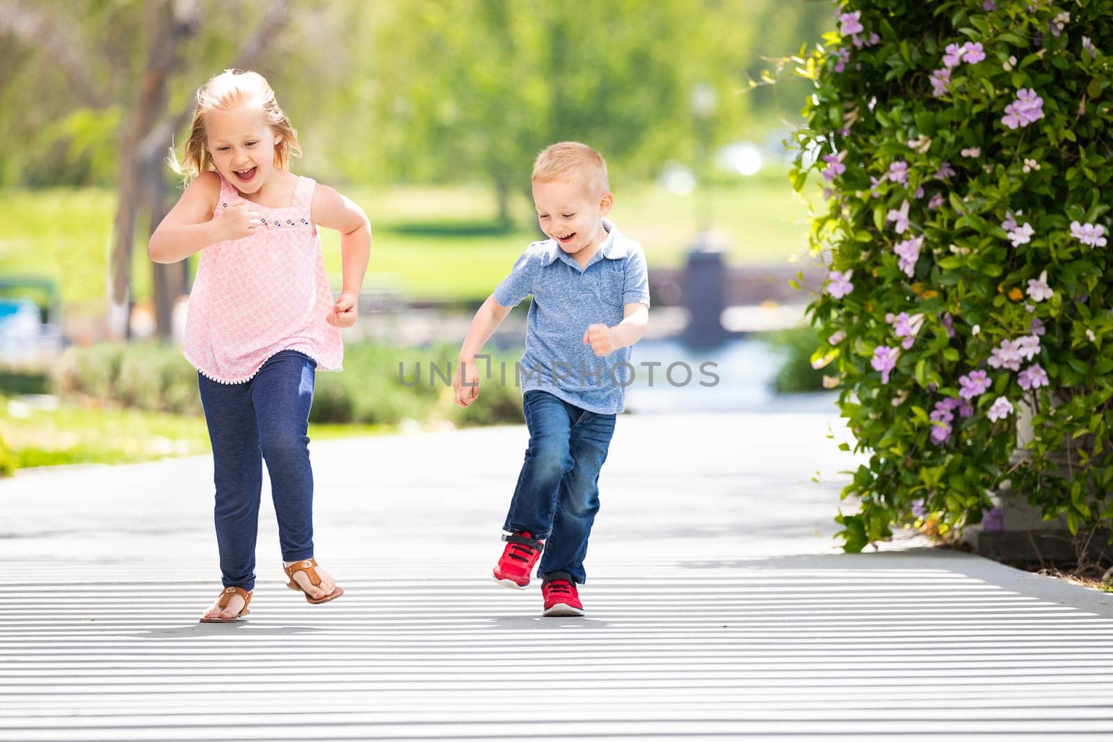 Young Sister and Brother Having Fun Running At The Park.