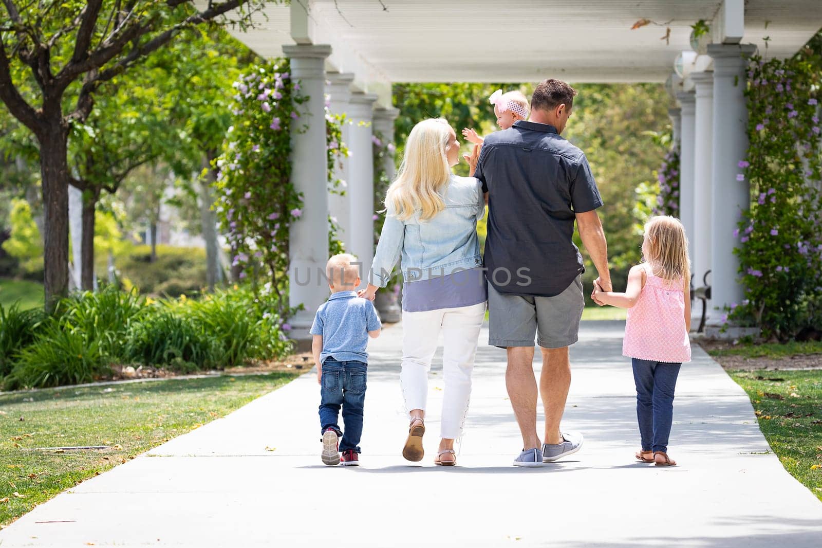 Young Caucasian Family Taking A Walk In The Park.