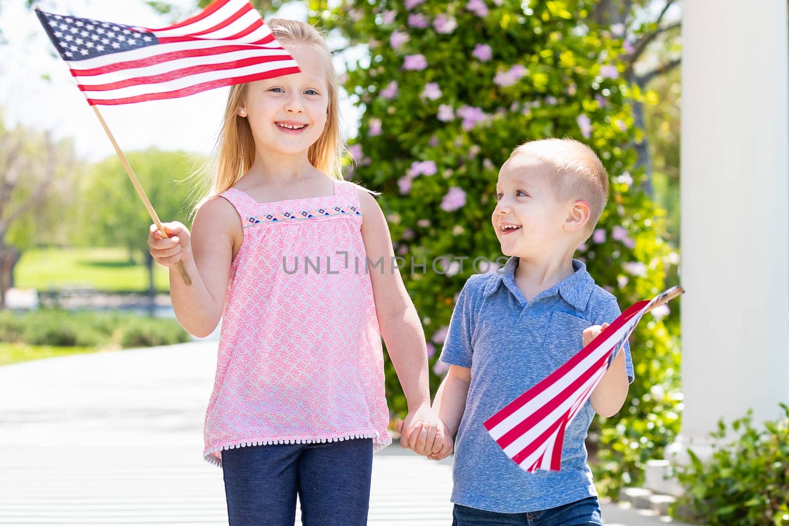 Young Sister and Brother Waving American Flags At The Park.