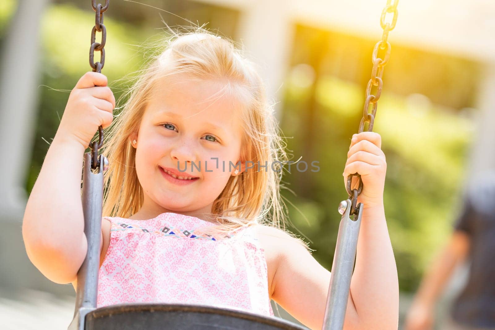 Pretty Young Girl Having Fun On The Swings At The Playground.
