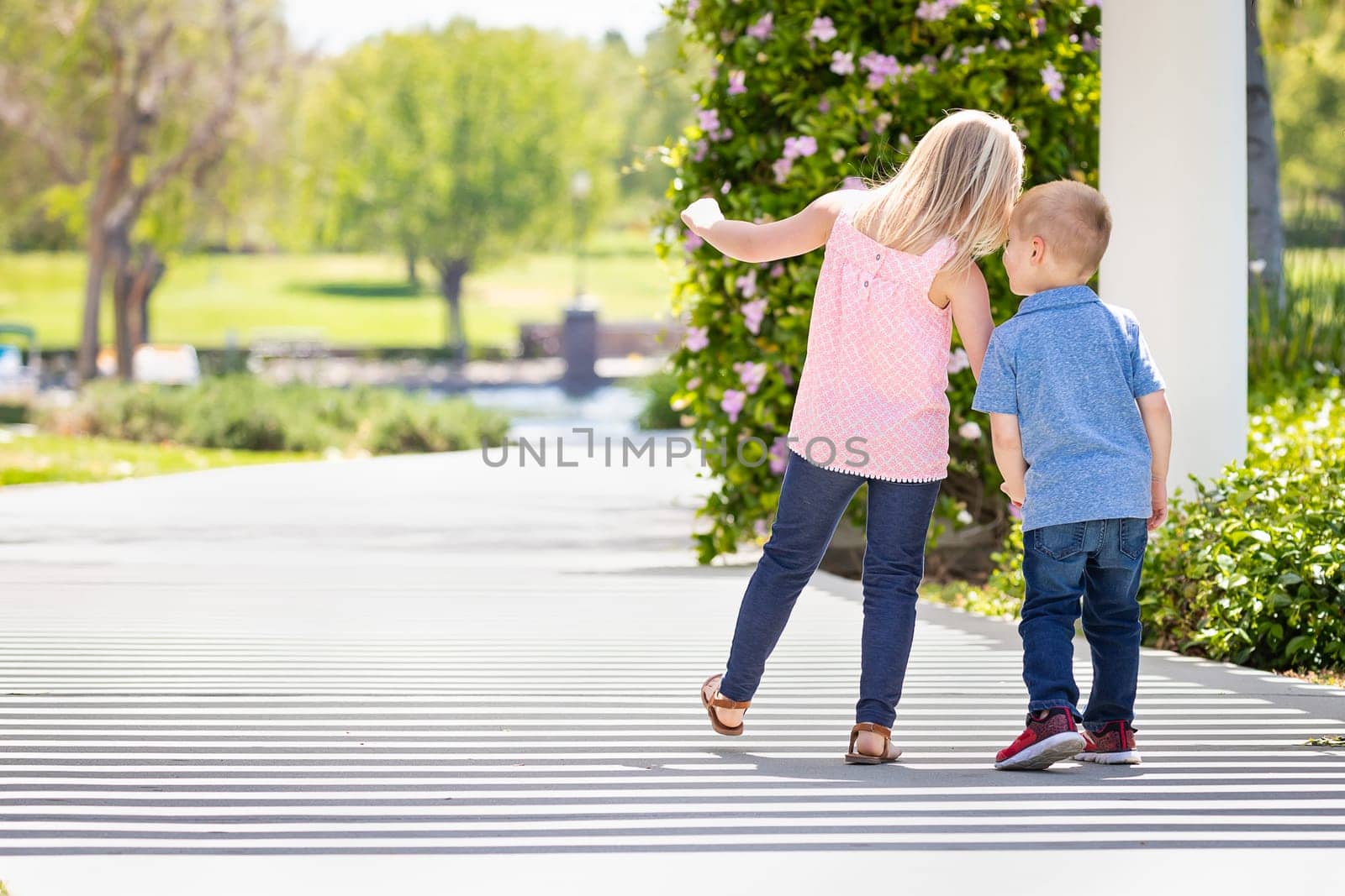 Young Sister and Brother Holding Hands And Walking At The Park.