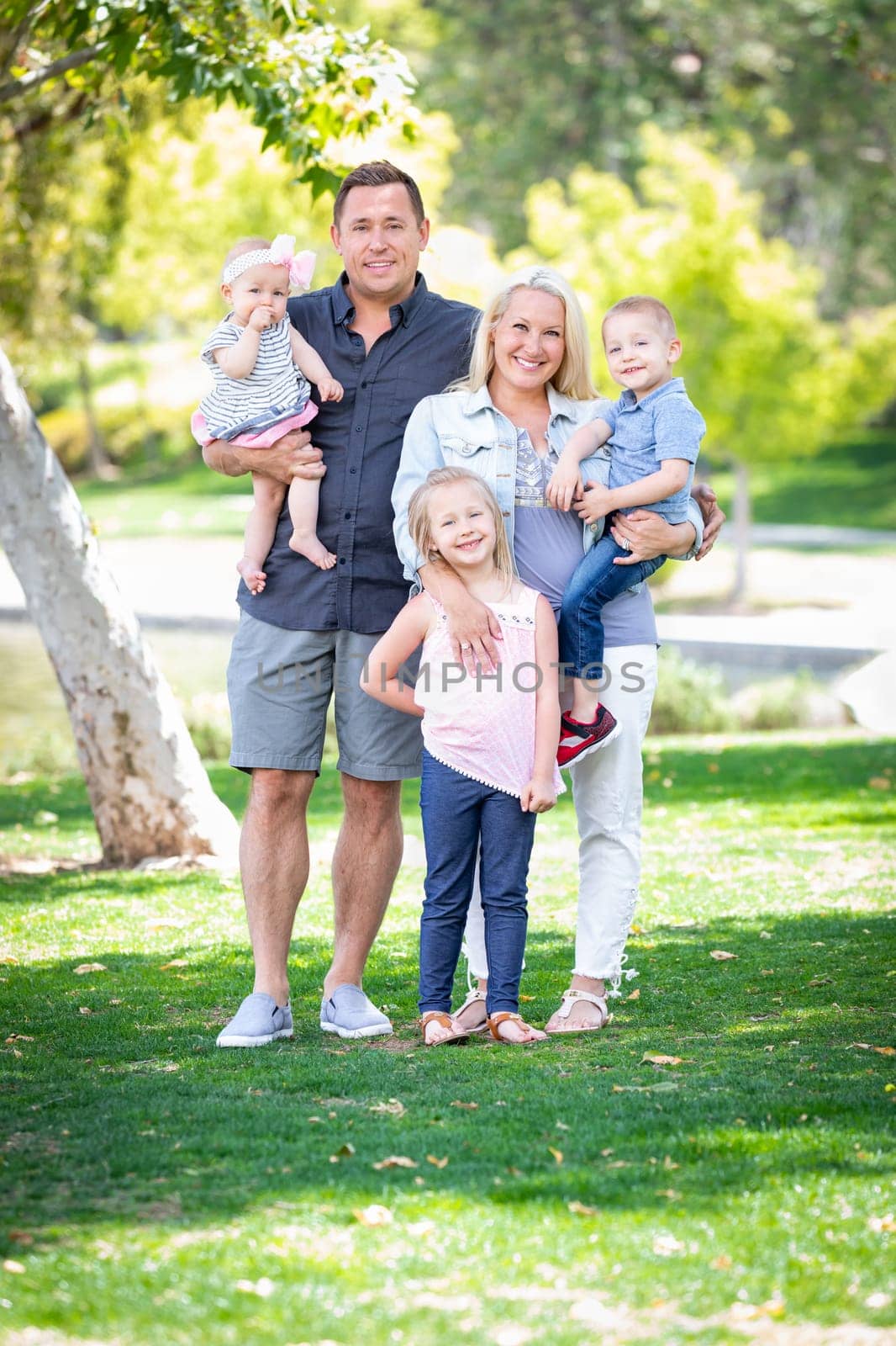 Happy Young Caucasian Family Portrait In The Park.