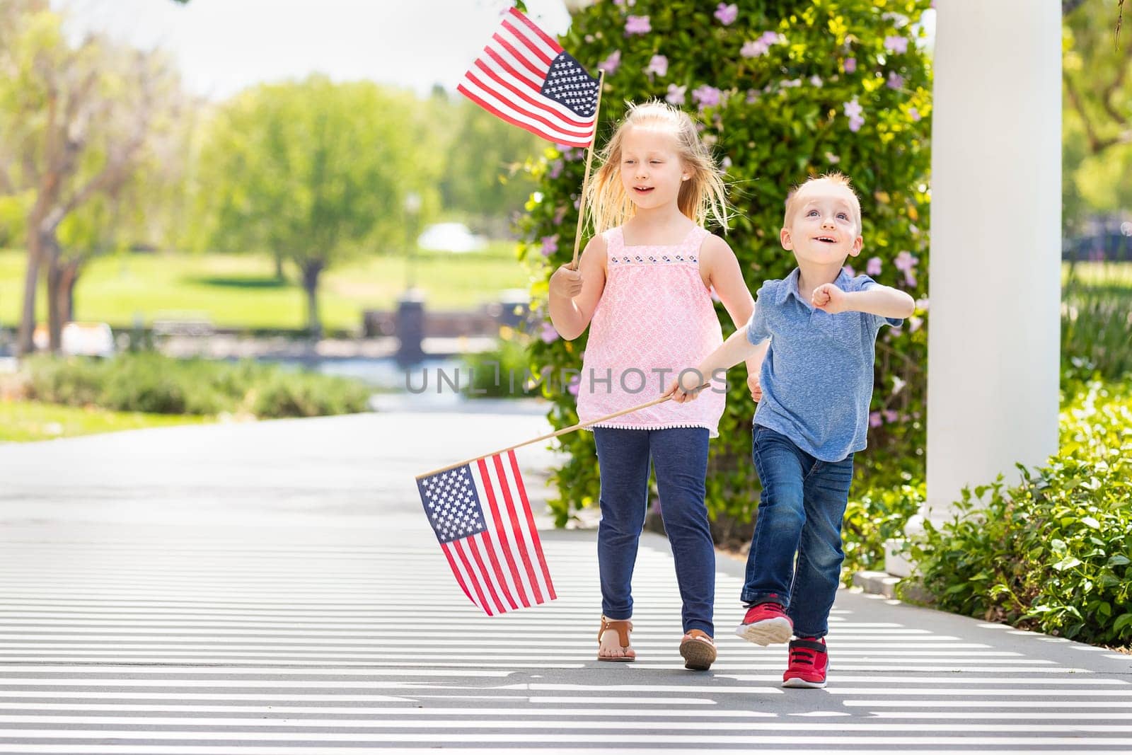 Young Sister and Brother Waving American Flags At The Park.