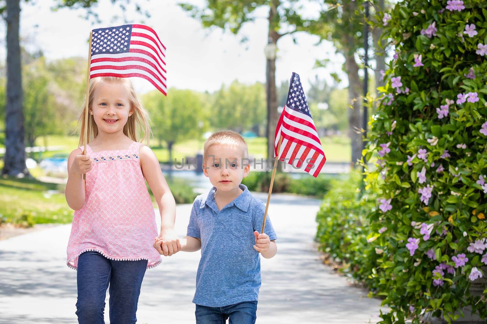Young Sister and Brother Waving American Flags At The Park.