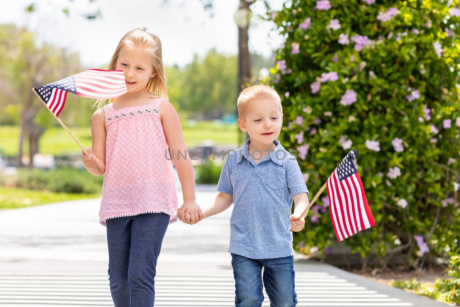 Young Sister and Brother Waving American Flags At The Park.