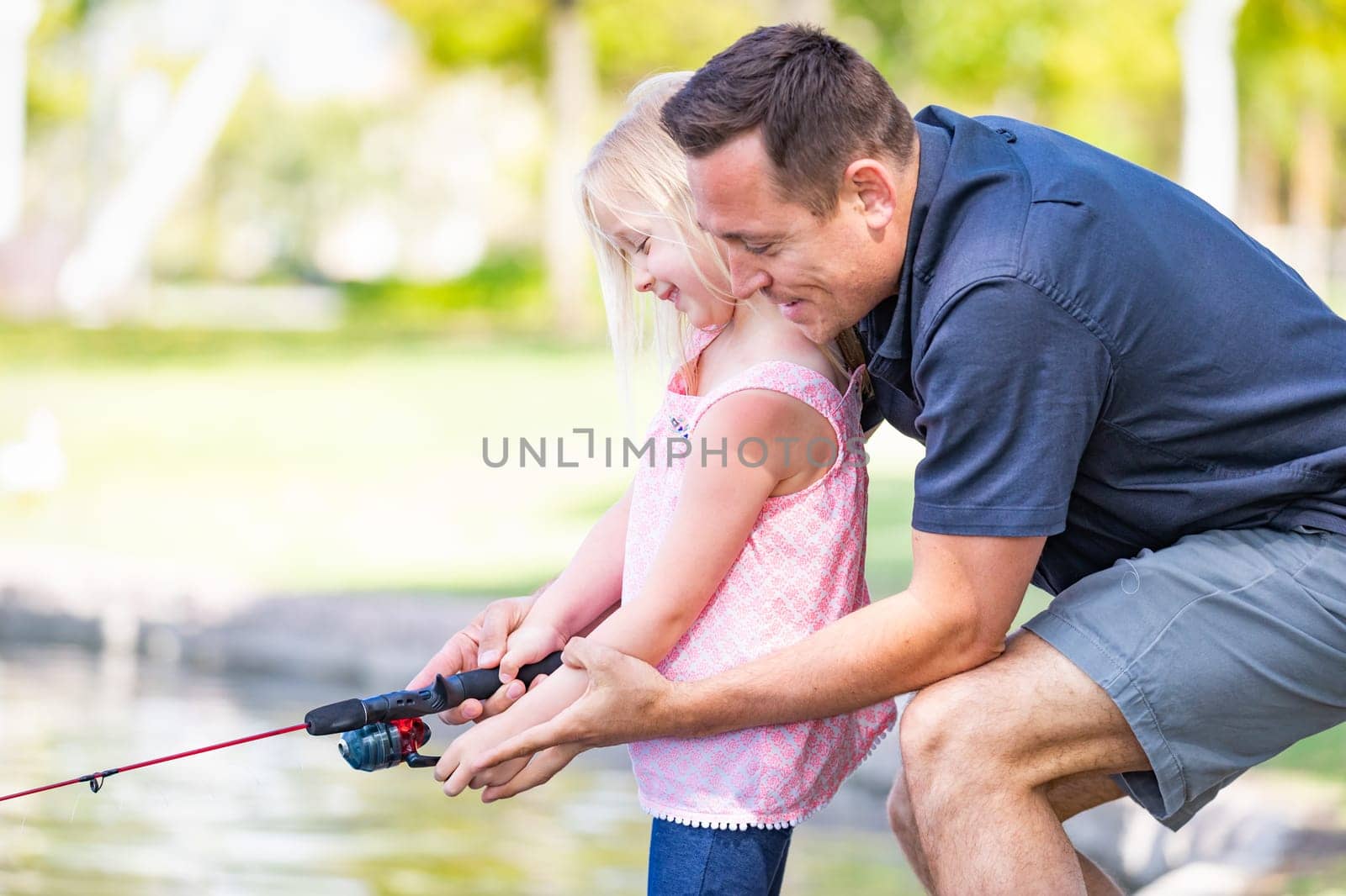 Young Caucasian Father and Daughter Having Fun Fishing At The Lake.