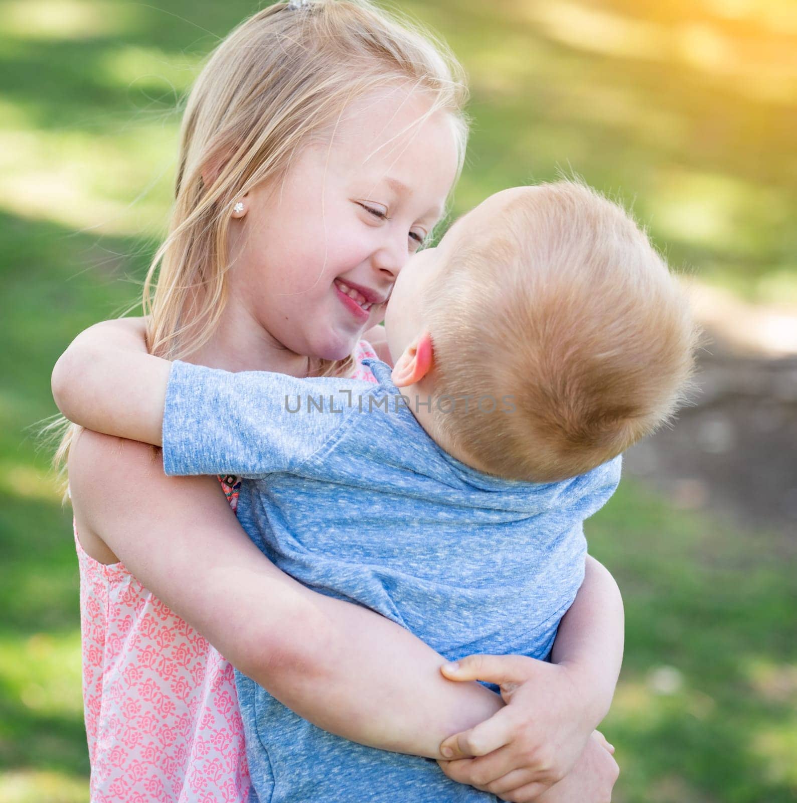 Young Brother and Sister Hugging At The Park.