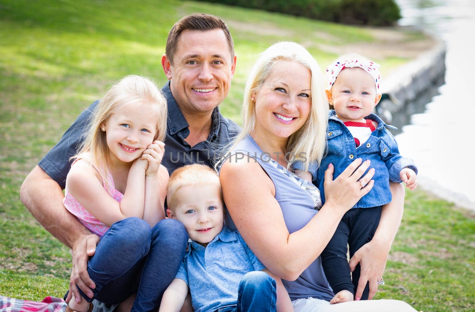 Happy Young Caucasian Family Portrait In The Park.