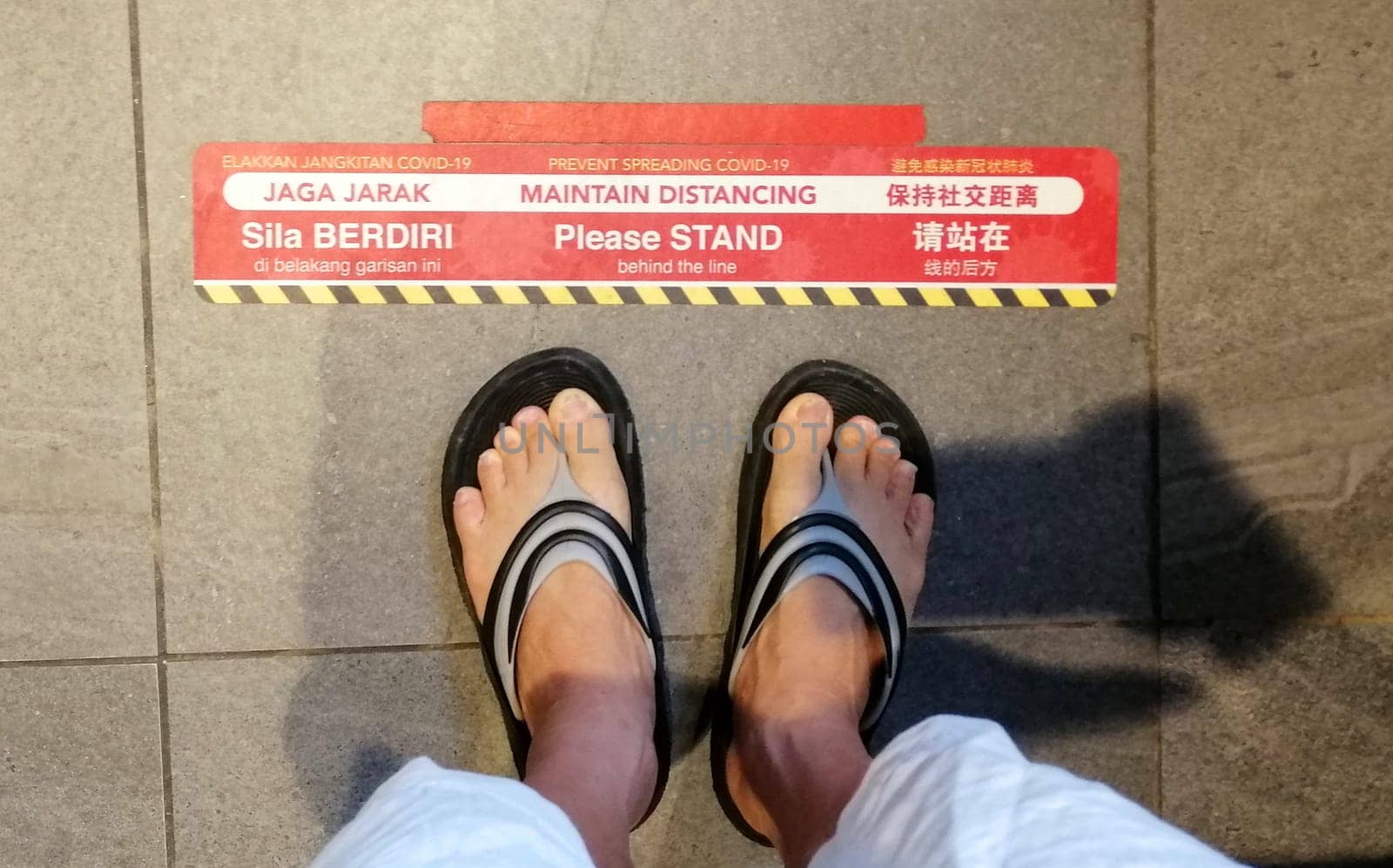 Lines pasted on floors in chinese, malay and english language to provide people a safe distance from each other in supermarket during the Coronavirus pandemic at Kuala Lumpur, Malaysia.