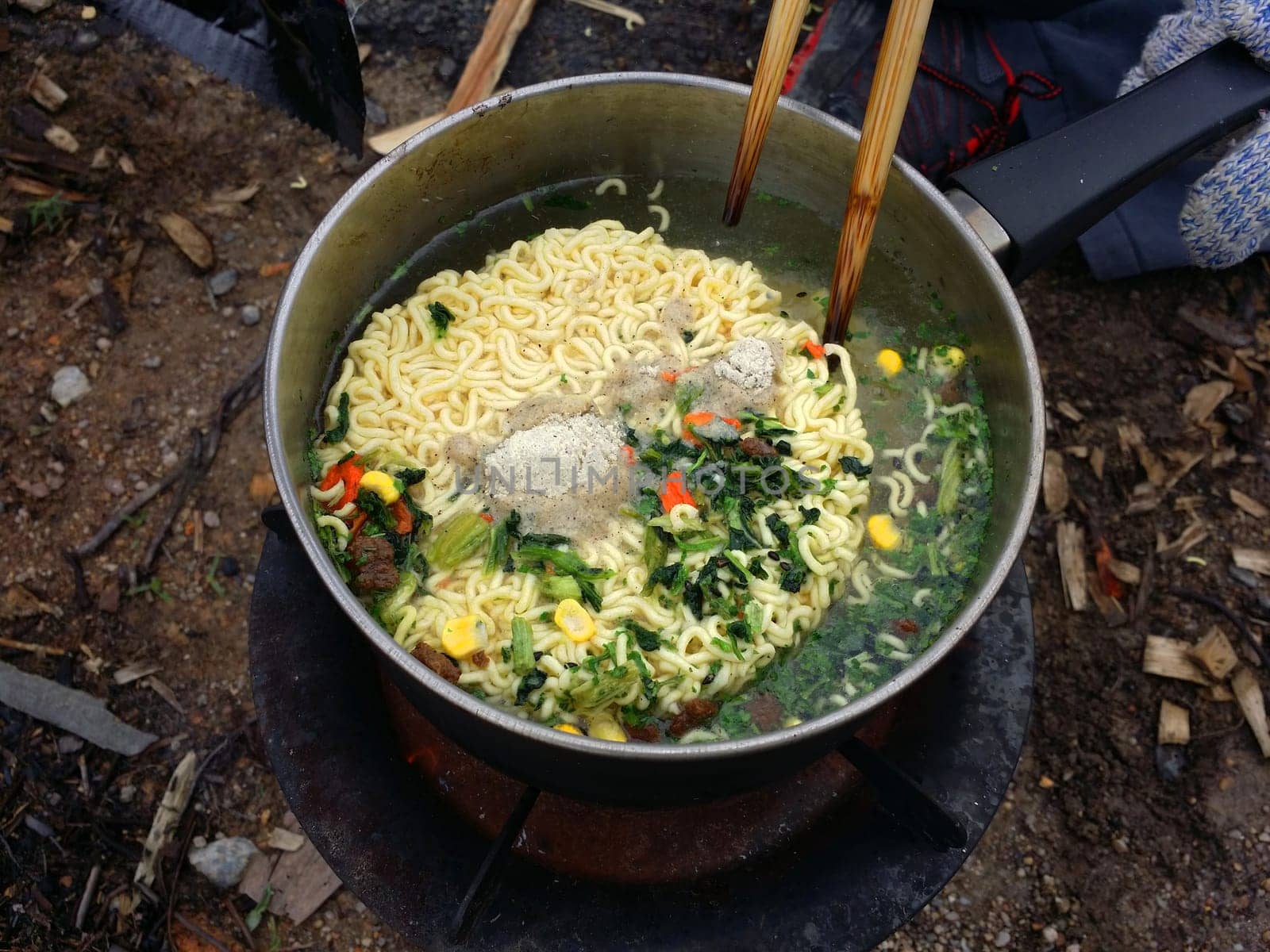 Cooking instant nodles at outdoors in black pot at picnic on fire.
