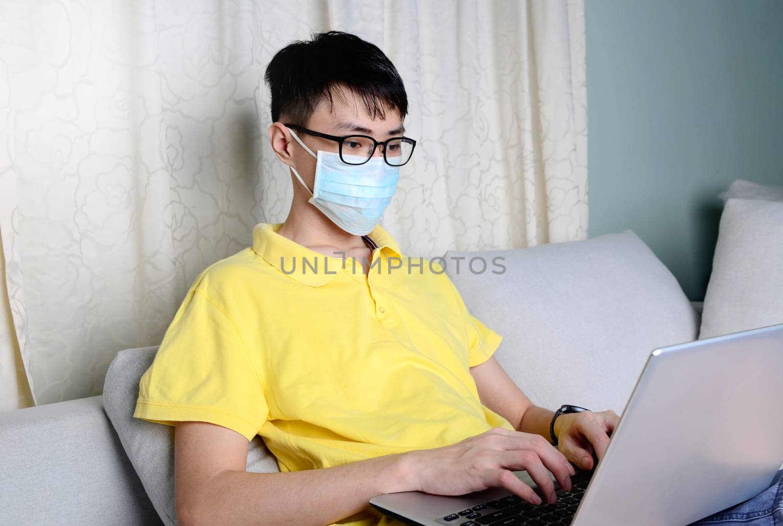 An asian man is working from home during pandemic coronavirus  Covid-19. Ccoronavirus covid 19 infected patient in quarantine room using computer.....