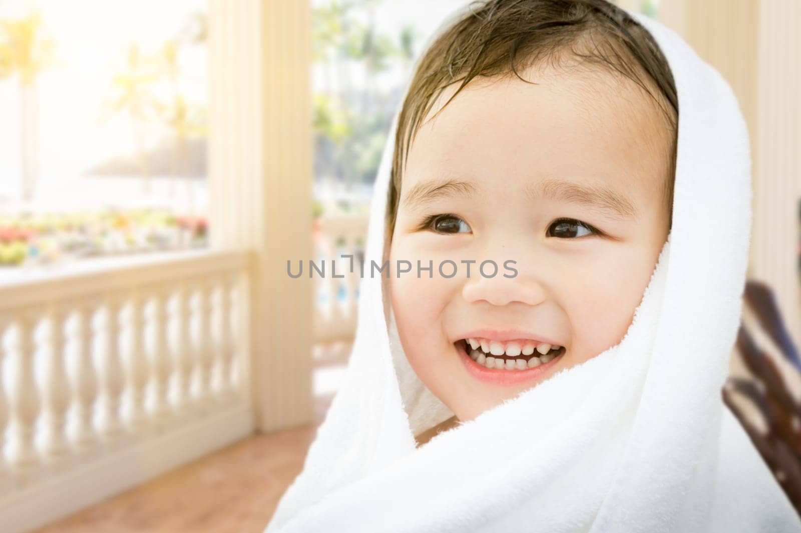 Happy Cute Mixed Race Chinese and Caucasian Boy On Tropical Patio Wrapped In A Towel.