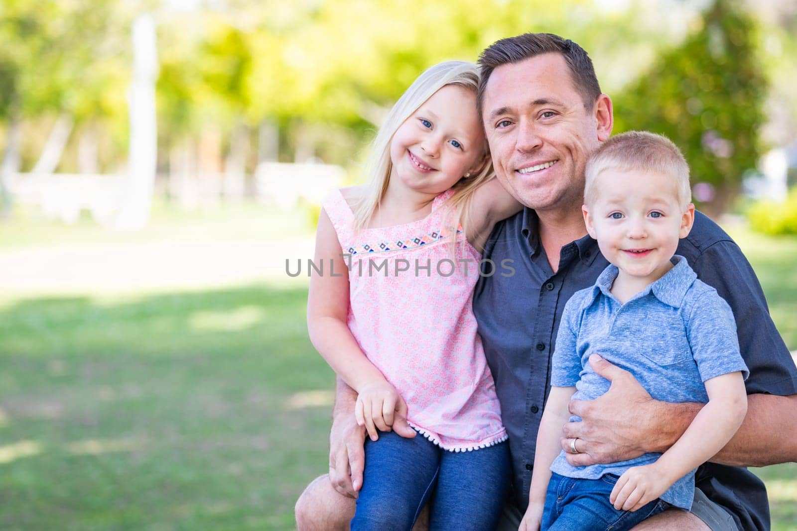 Young Caucasian Dad, Son and Daughter Having Fun In The Park.