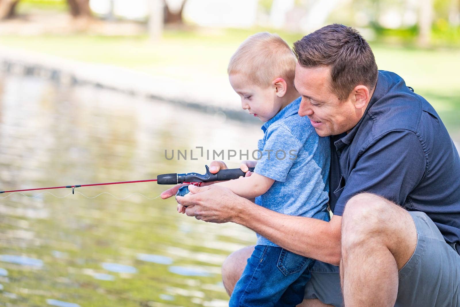 Young Caucasian Father and Son Having Fun Fishing At The Lake.