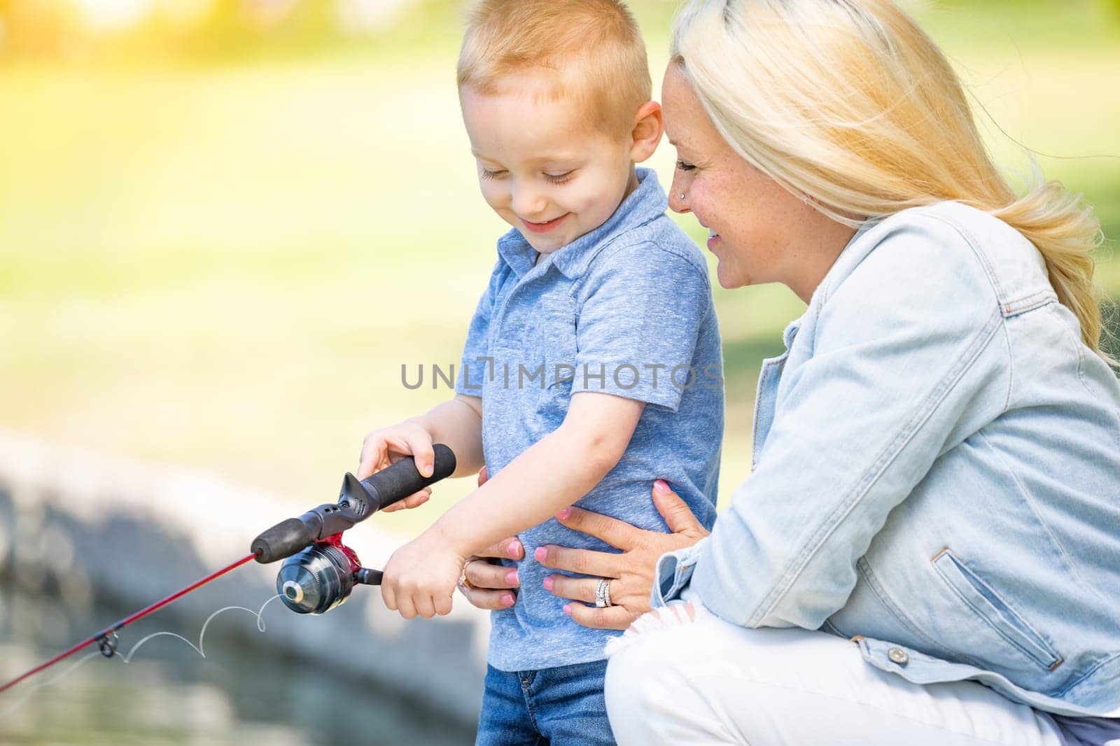 Young Caucasian Mother and Son Having Fun Fishing At The Lake.
