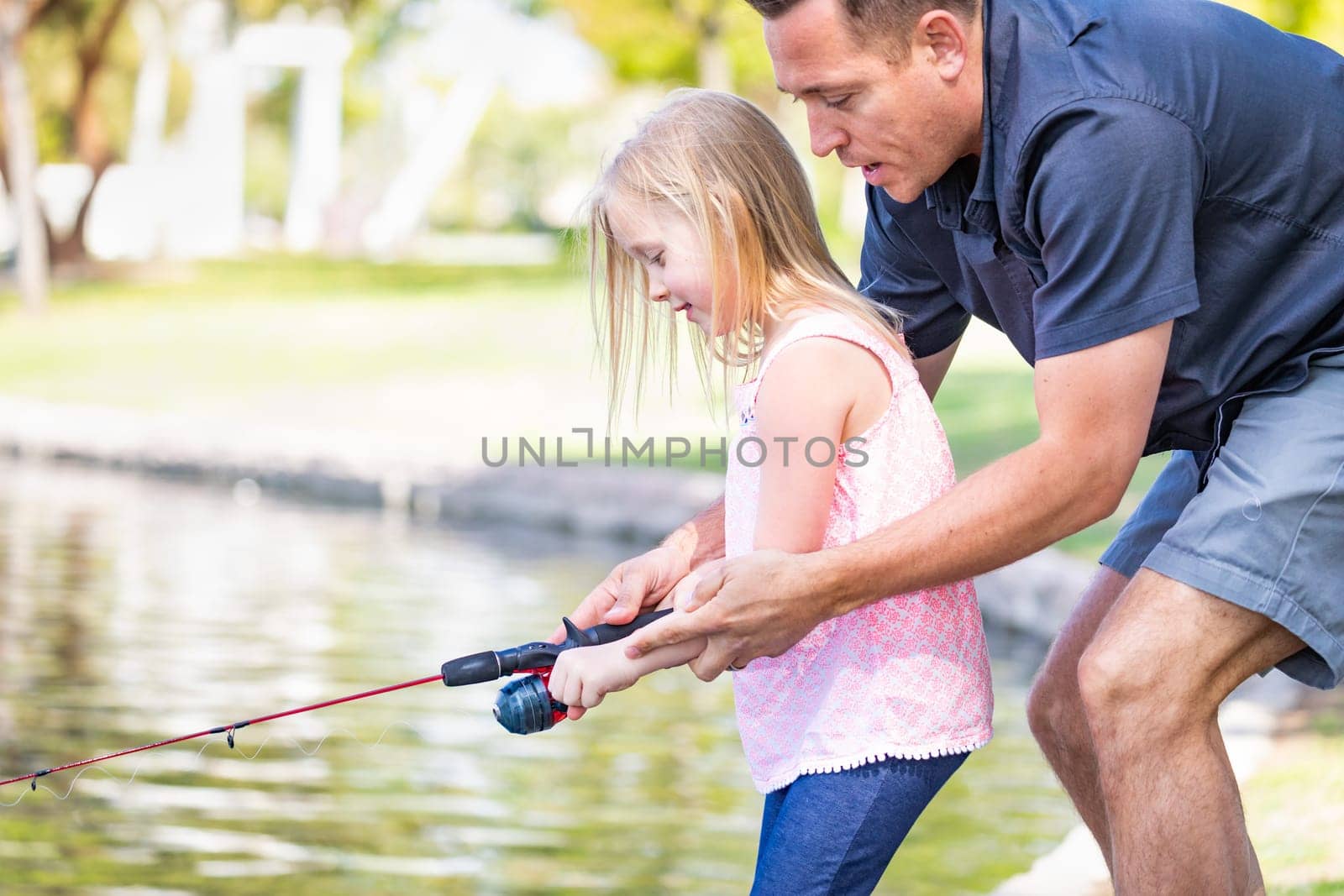 Young Caucasian Father and Daughter Having Fun Fishing At The Lake.