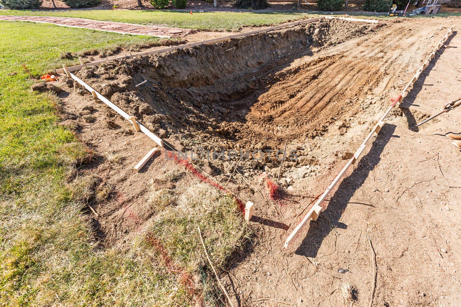 Freshly Dug Hole In Yard Preparing For Swimming Pool Installation.