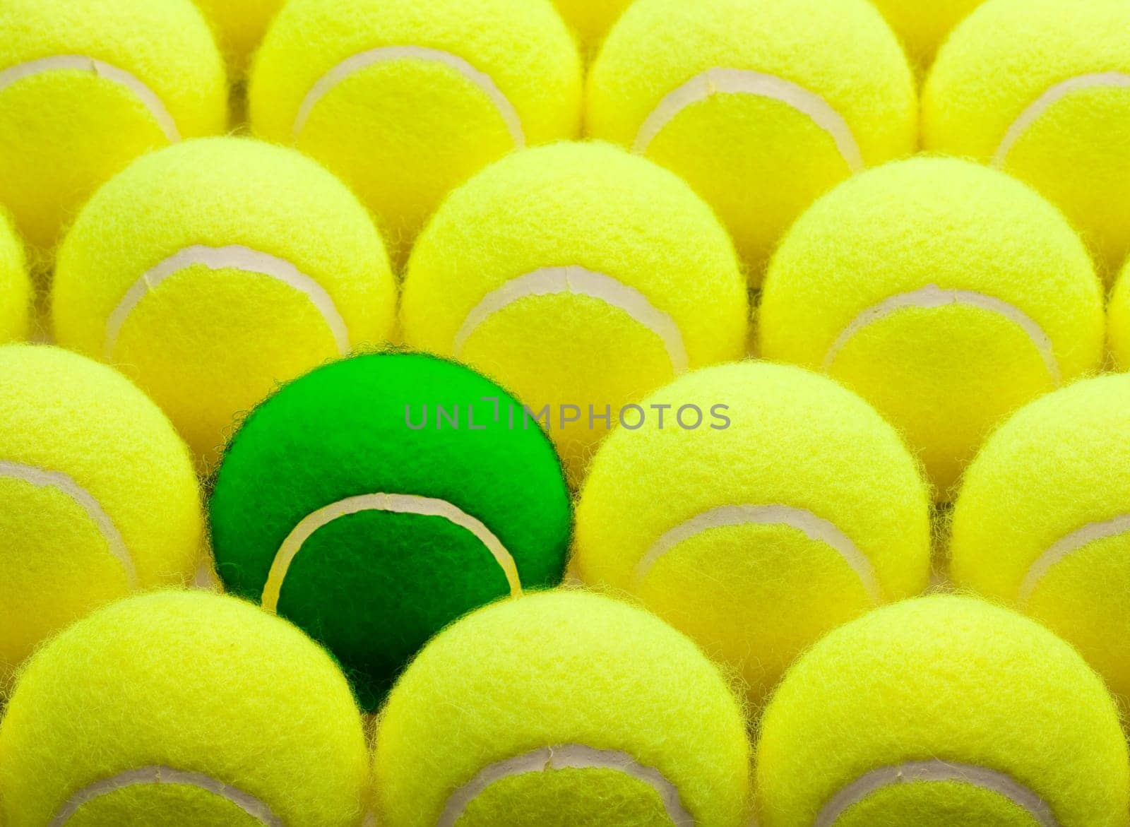 Group of Yellow Tennis Balls and One Green One.