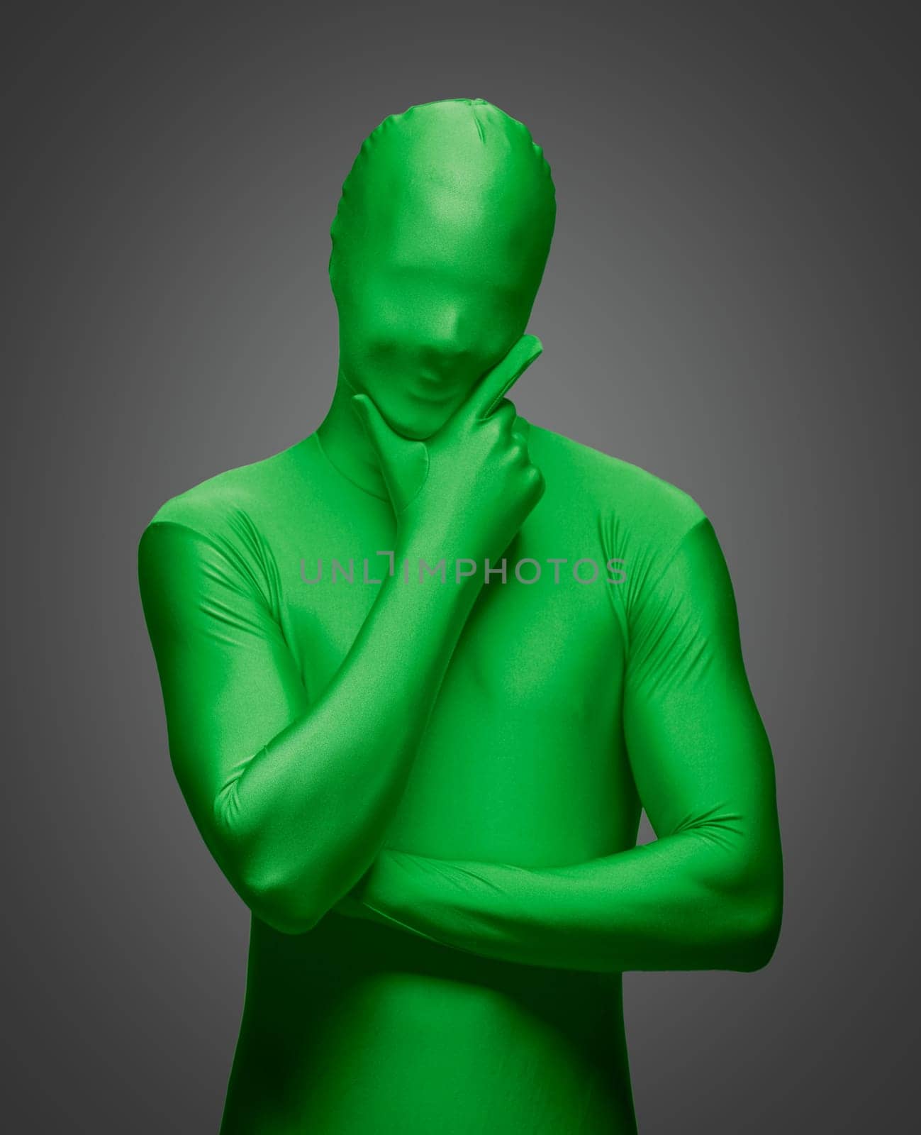 Thinking Man with Hand on Chin Wearing Full Green Nylon Bodysuit on a Grey Background..