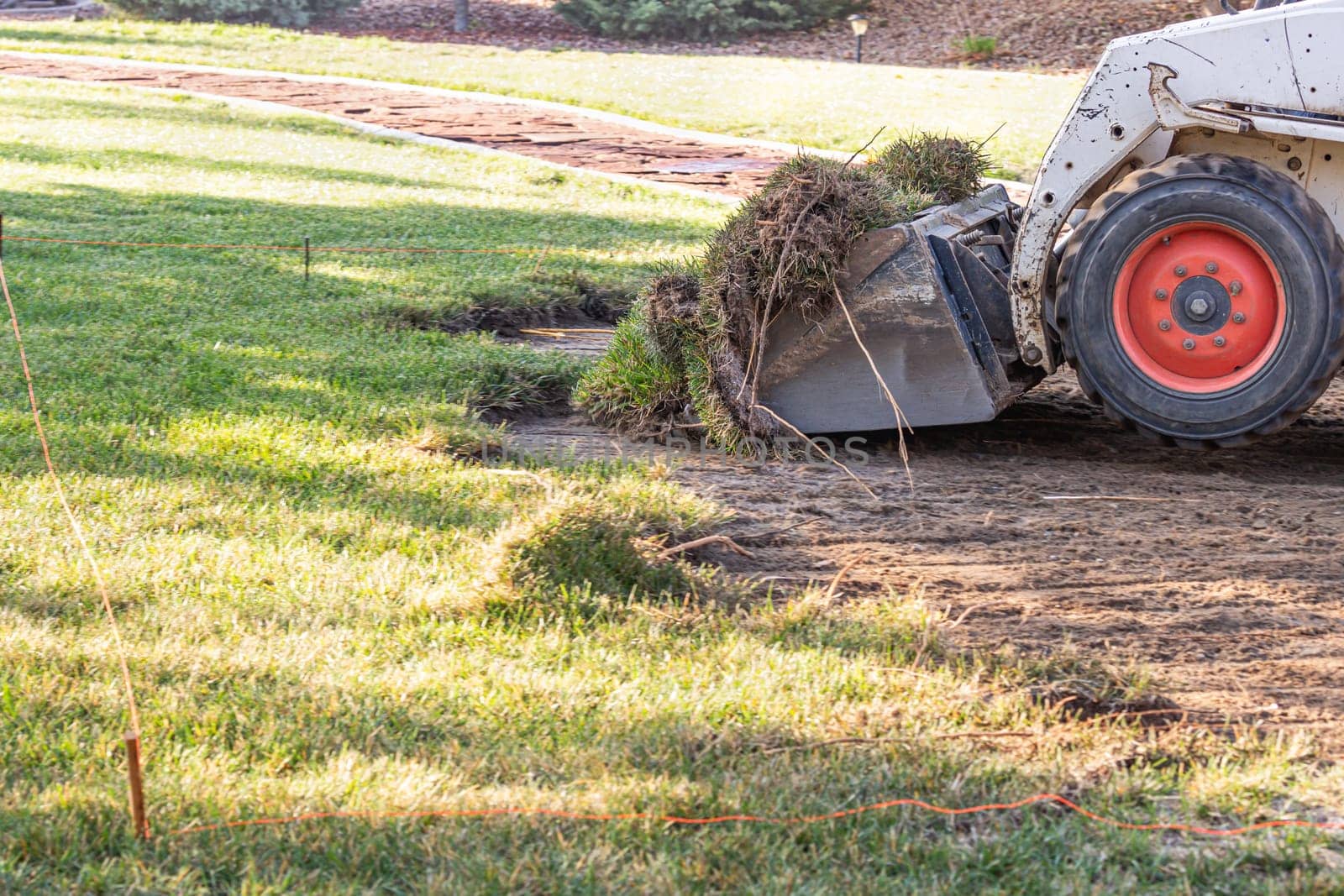 Small Bulldozer Removing Grass From Yard Preparing For Pool Installation.