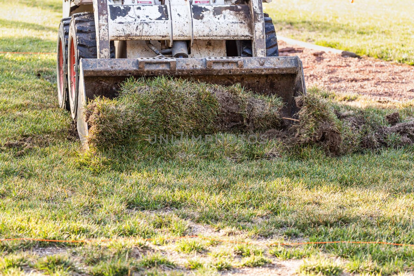 Small Bulldozer Removing Grass From Yard Preparing For Pool Installation.