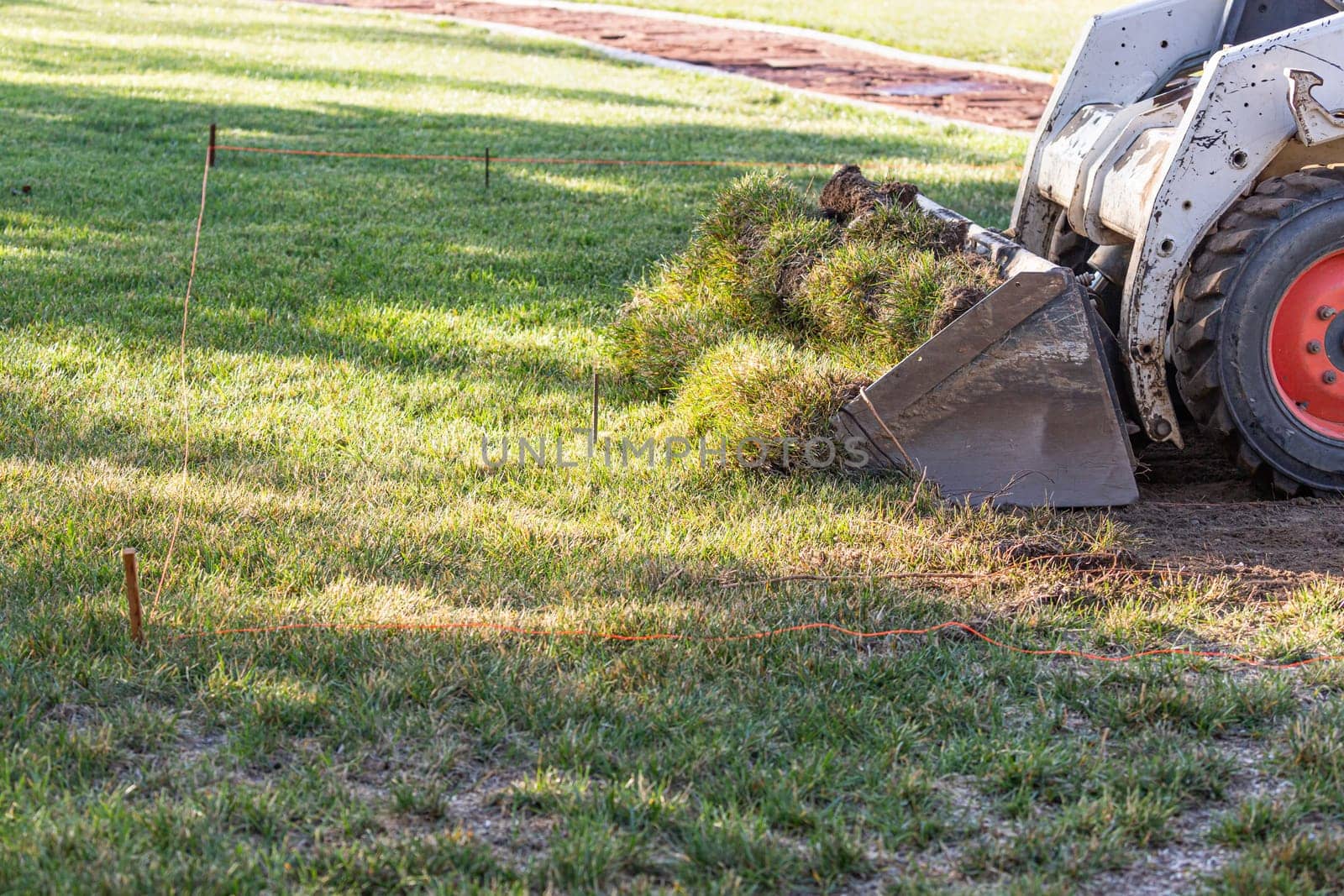 Small Bulldozer Removing Grass From Yard Preparing For Pool Installation.