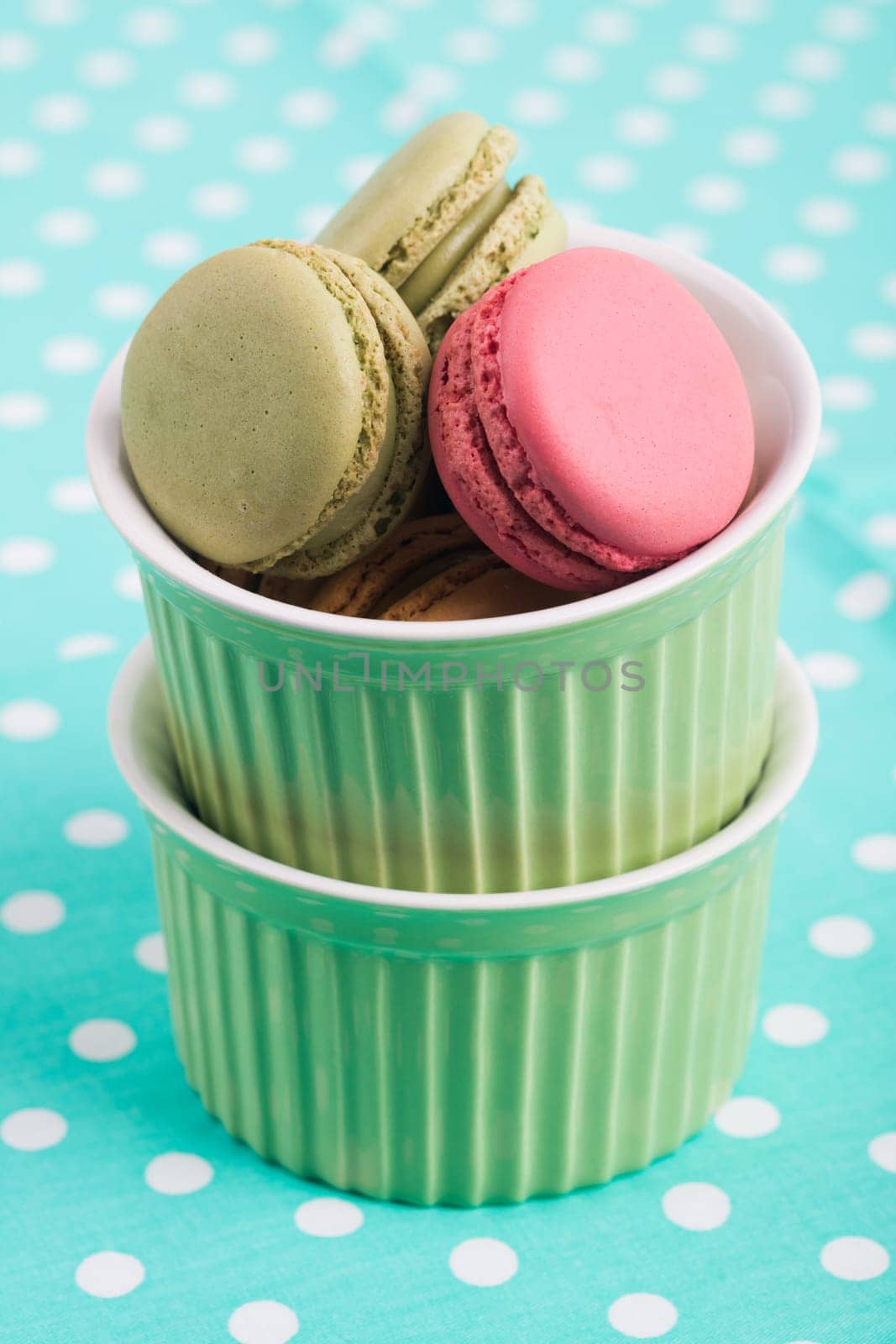 Sweet Macarons with green bowls and green fabric background