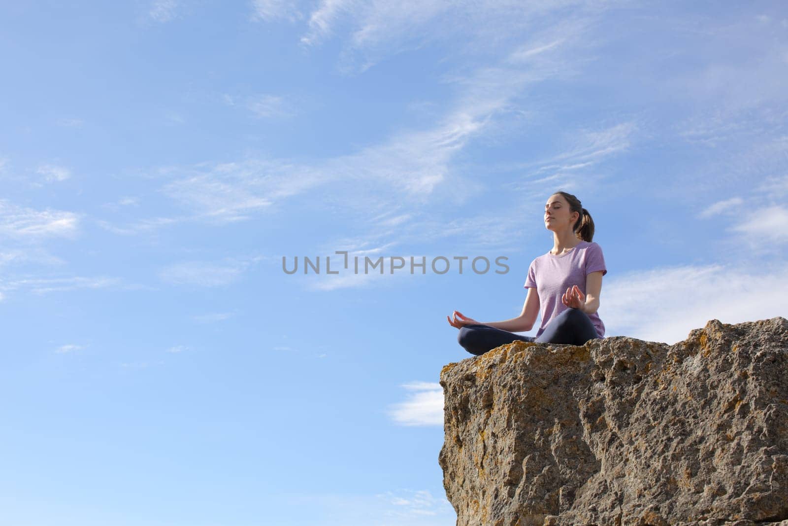 Yogi practicing yoga in the top of a cliff