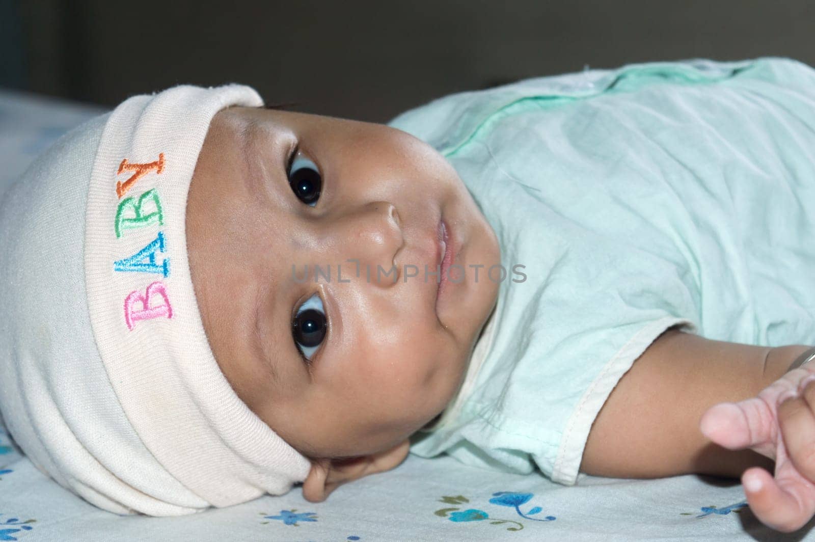 Upside down Closeup cute face of newborn baby boy lying on bed and Looking at camera. Sweet little infant toddler Closeup portrait. Indian ethnicity. Front view. Child Health care medical background.