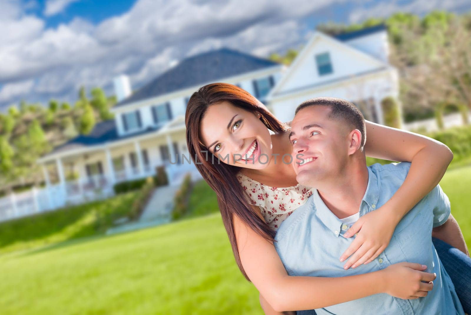 Playful Young Military Couple Outside A Beautiful New Home.