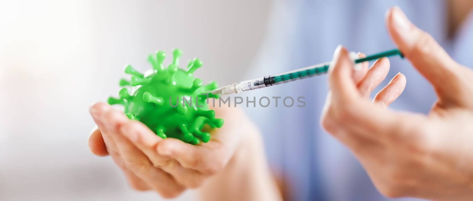 Medical worker holding a model of coronavirus and a syringe. Concept of vaccination aganst pandemic of Covid-19. Idea of fighting with pandemic.