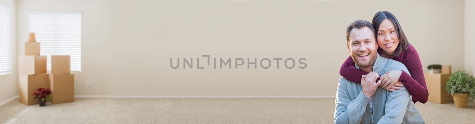 Mixed Race Caucasian and Chinese Couple Inside Empty Room with Moving Boxes Banner.