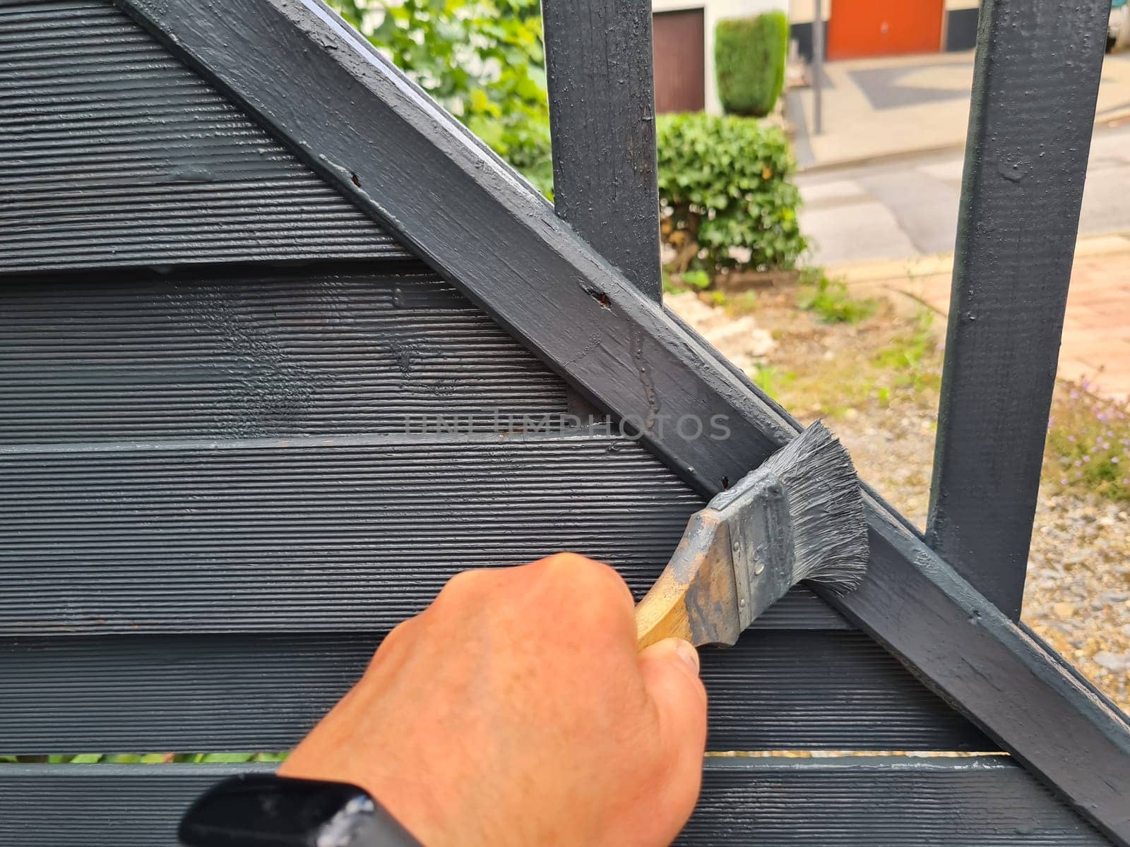 Brushing garden fence with brush - close-up