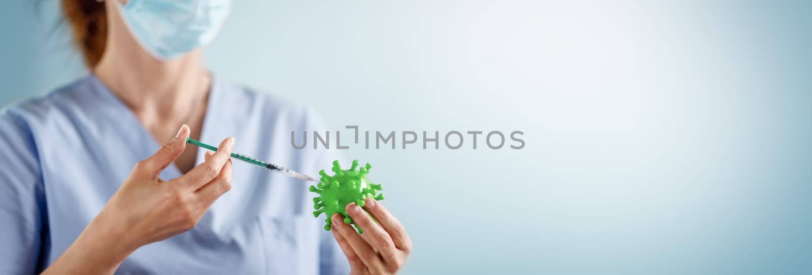 Medical worker holding a model of coronavirus and a syringe. Concept of vaccination aganst pandemic of Covid-19. Idea of fighting with pandemic.