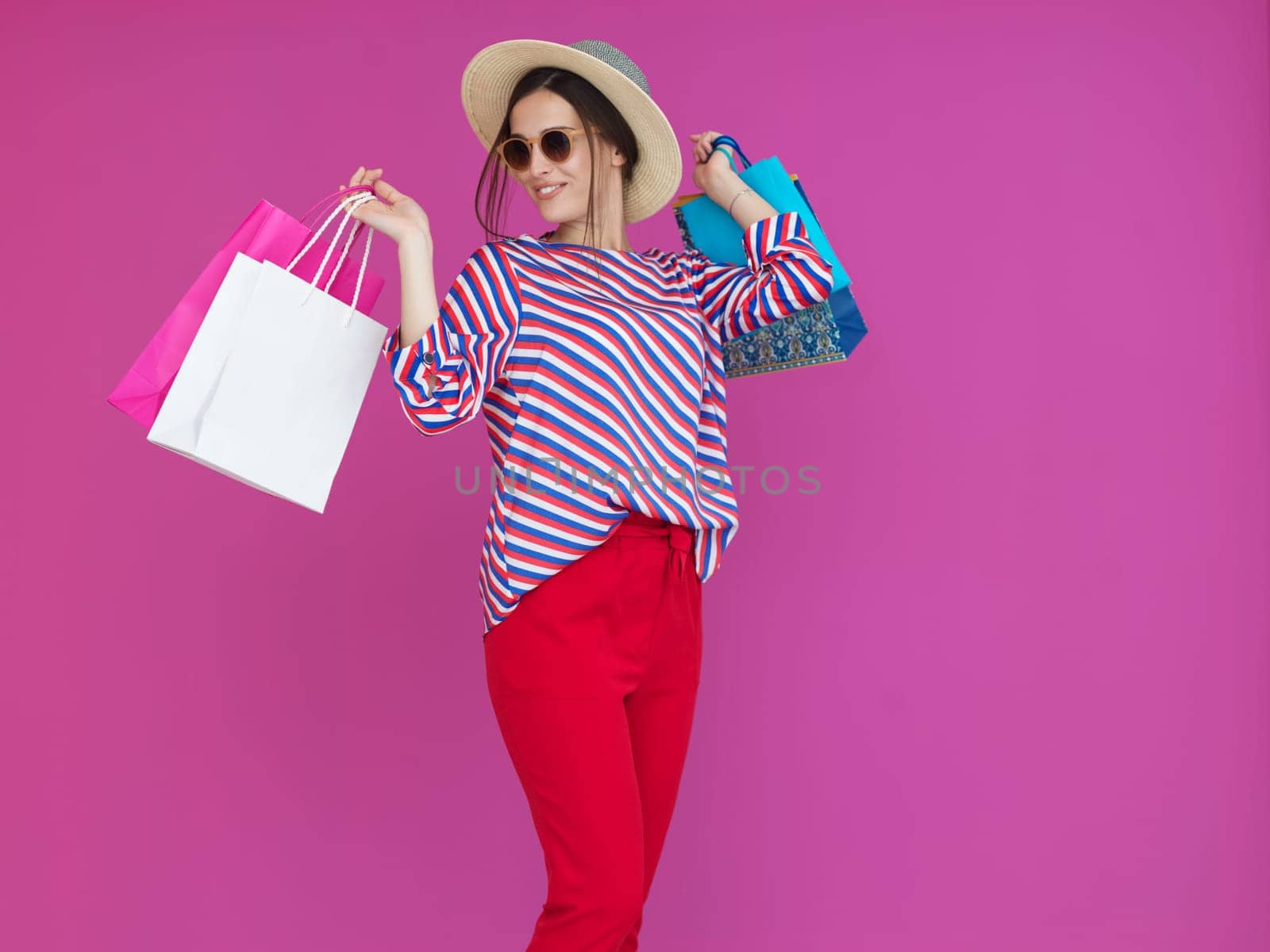 Young woman with shopping bags on pink background. Happy girl posing with new purchases after a day of big sale. Black Friday concept