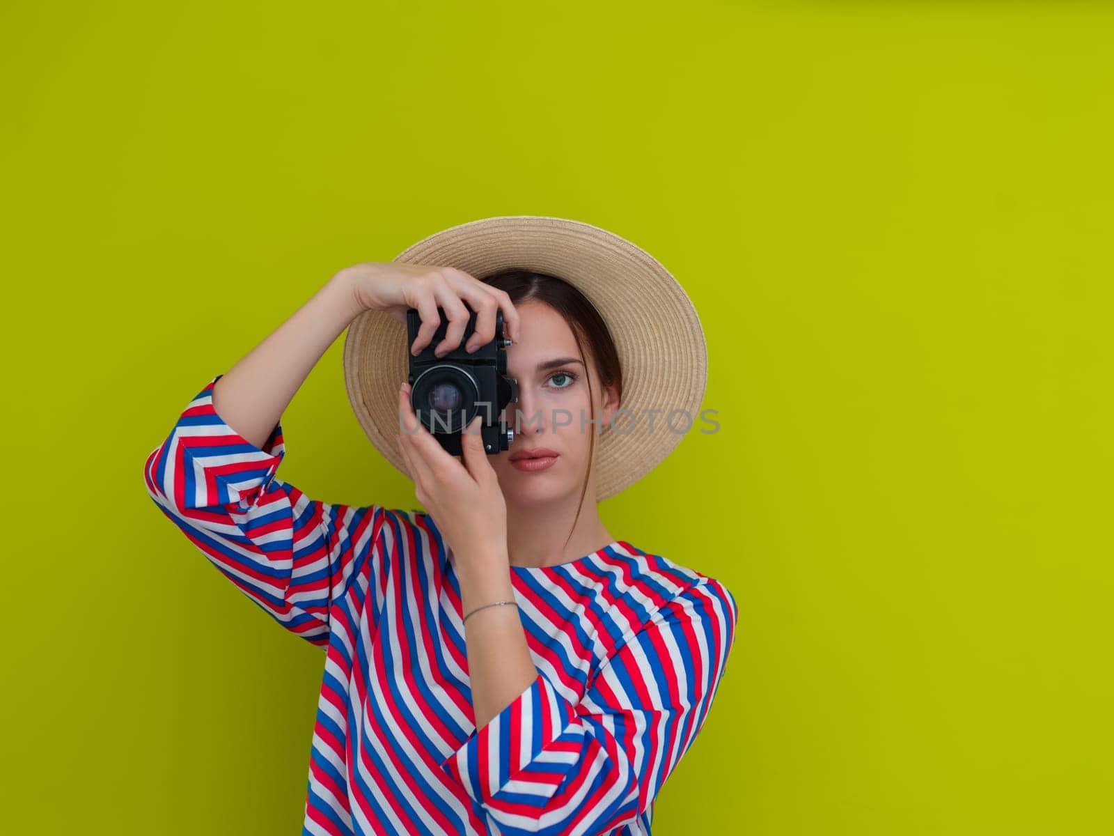 Portrait of beautiful female photographer shooting close up. Say cheese. Young smiling woman holding camera isolated on green background