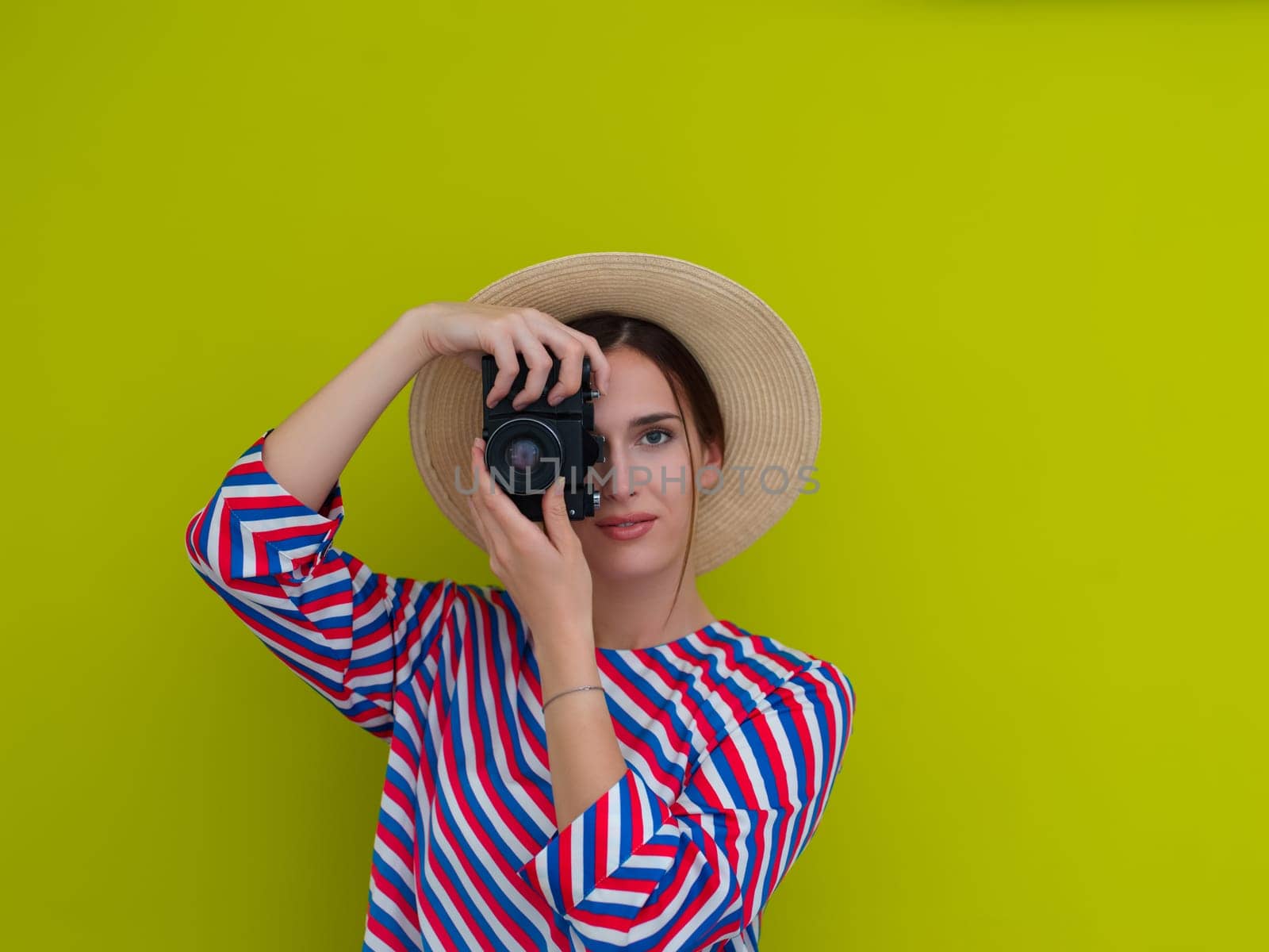 Portrait of beautiful female photographer shooting close up. Say cheese. Young smiling woman holding camera isolated on green background