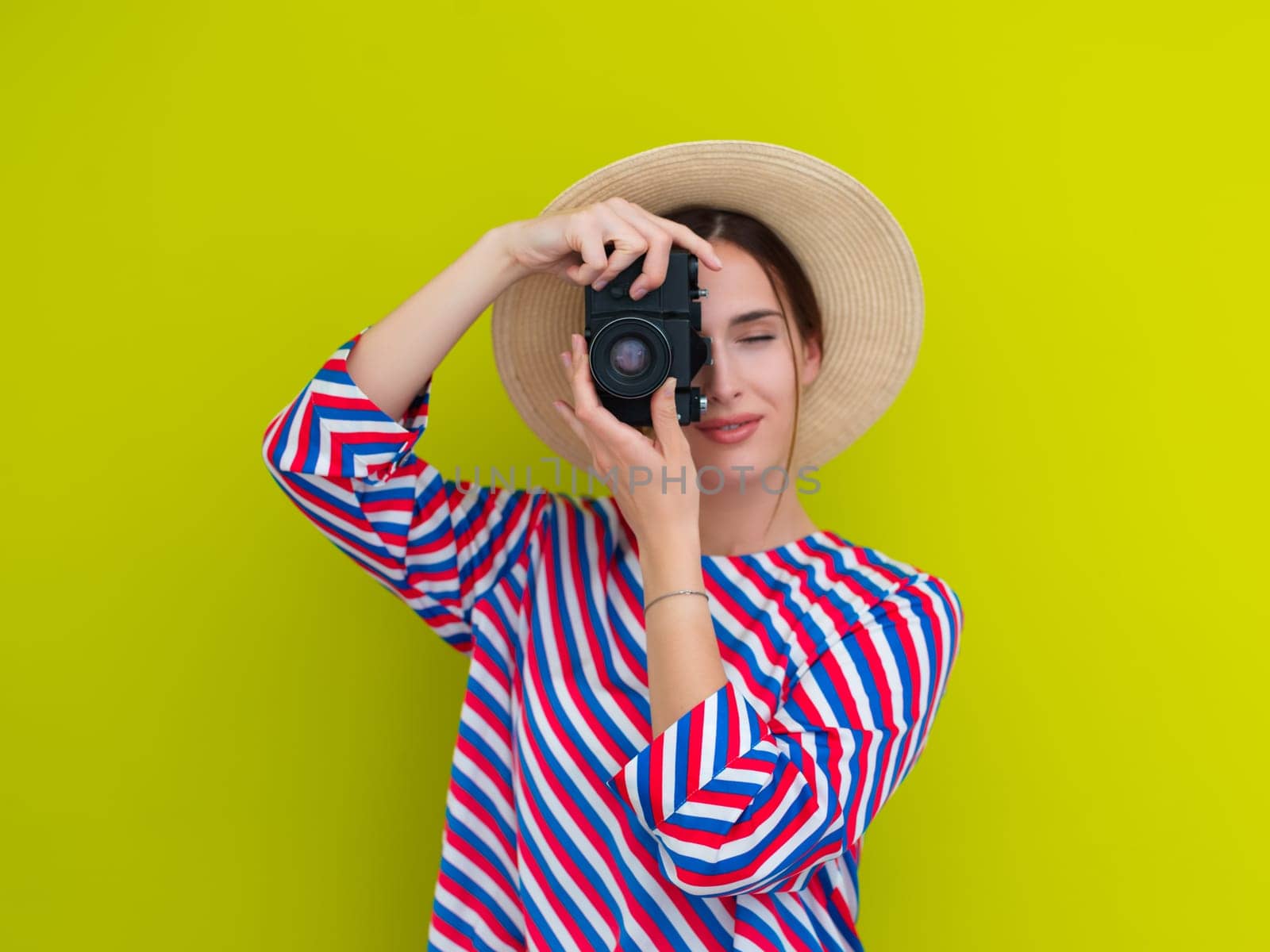 Portrait of beautiful female photographer shooting close up. Say cheese. Young smiling woman holding camera isolated on green background