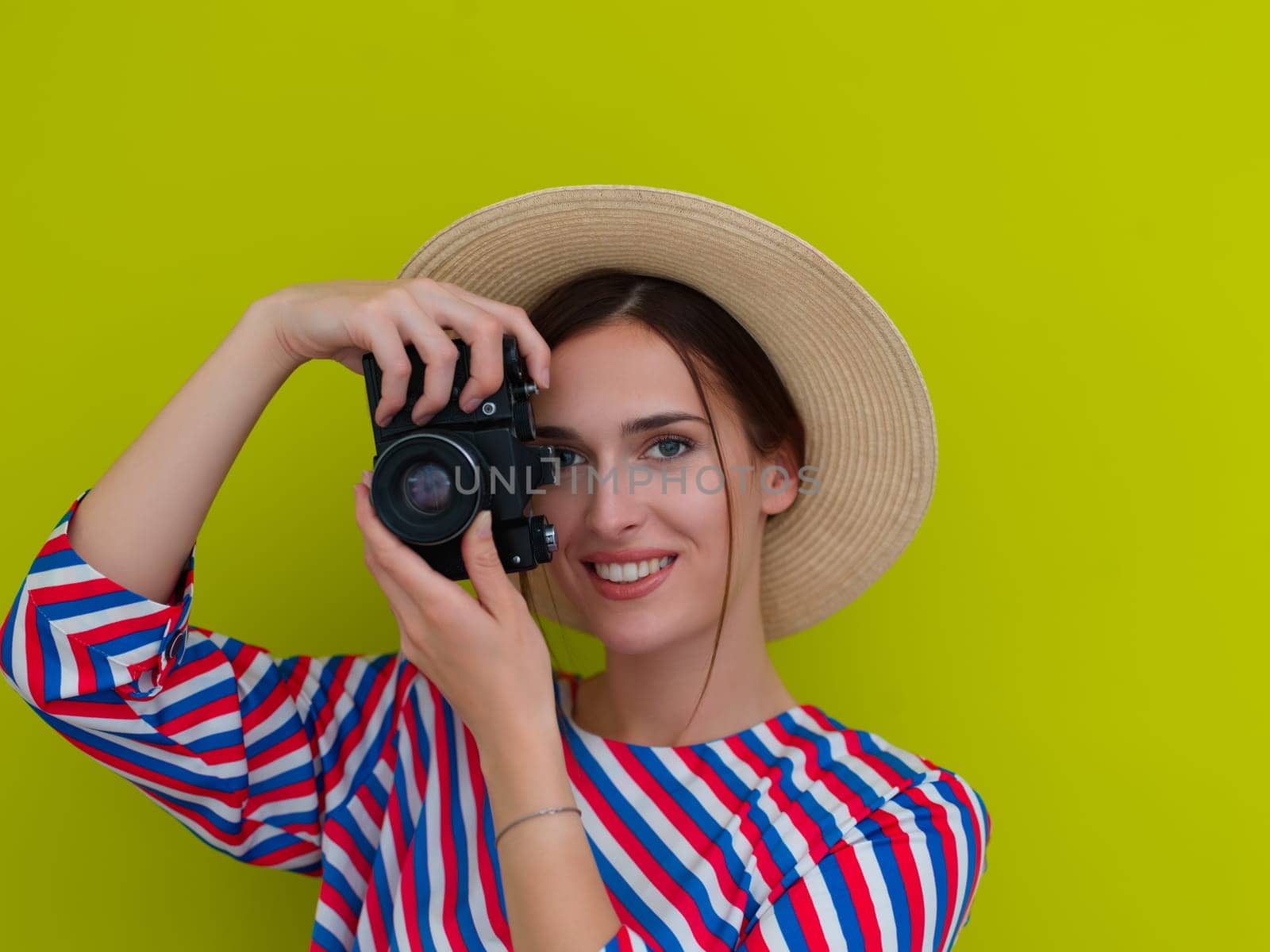 Portrait of beautiful female photographer shooting close up. Say cheese. Young smiling woman holding camera isolated on green background