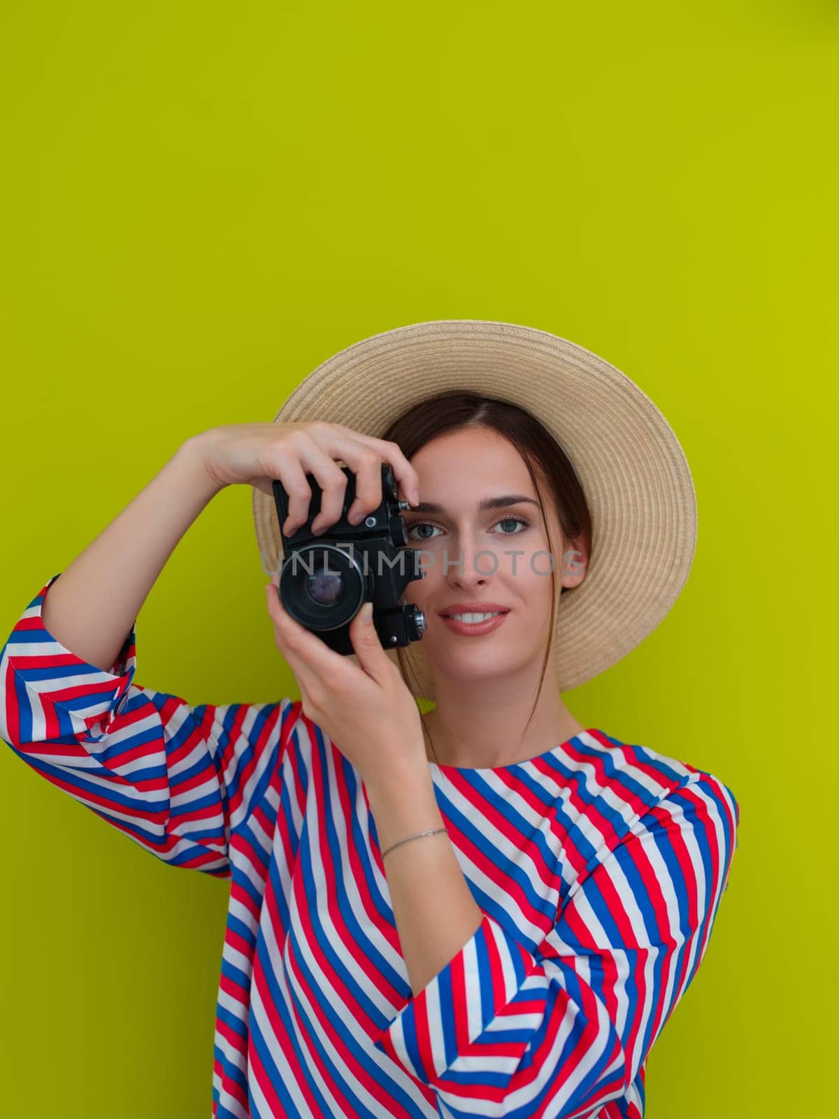 Portrait of beautiful female photographer shooting close up. Say cheese. Young smiling woman holding camera isolated on green background