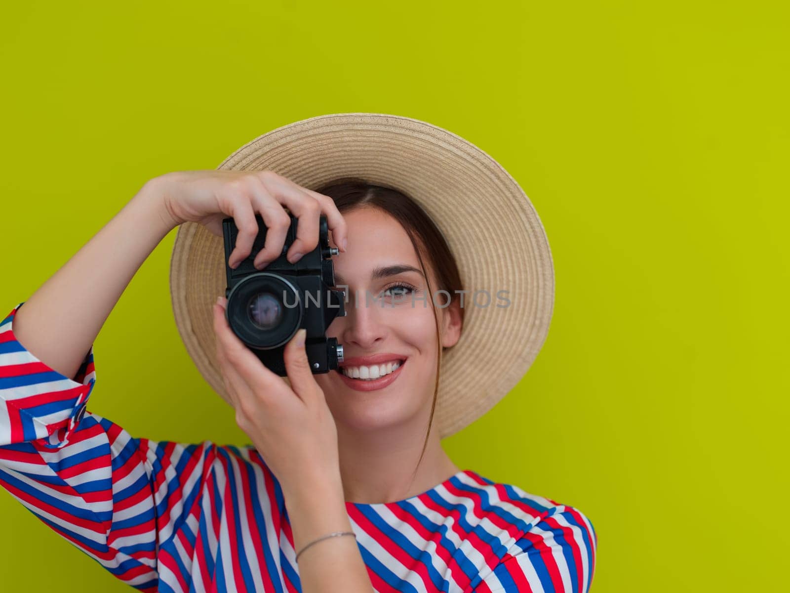 Portrait of beautiful female photographer shooting close up. Say cheese. Young smiling woman holding camera isolated on green background