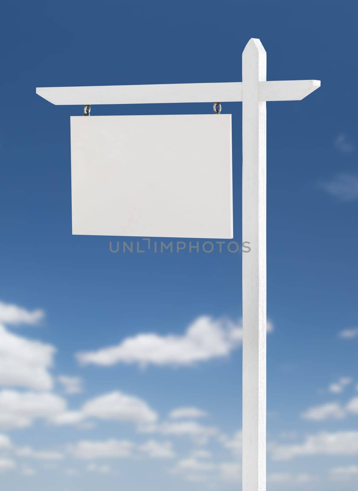 Blank Real Estate Sign Over A Blue Sky with Clouds.