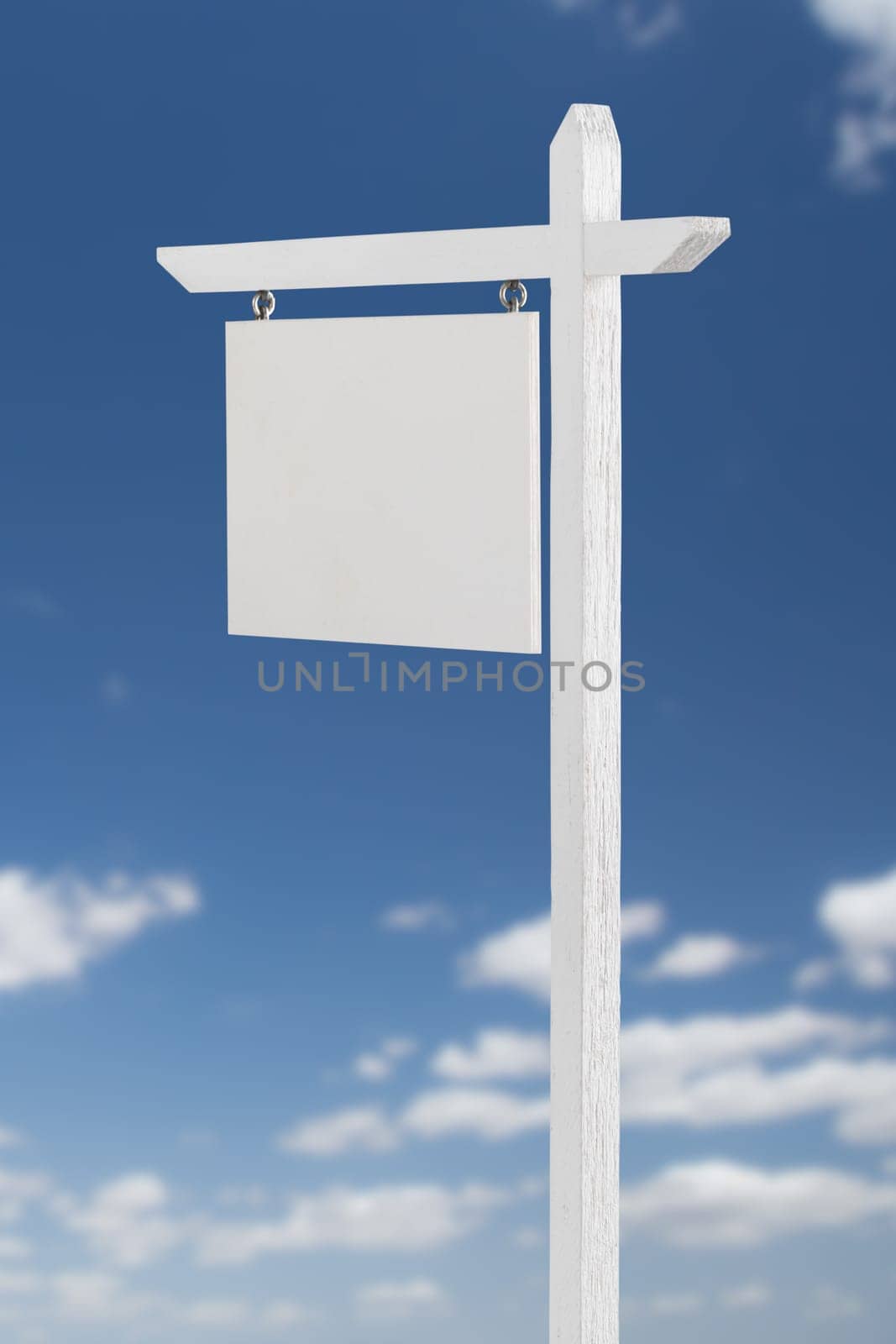 Blank Real Estate Sign Over A Blue Sky with Clouds.