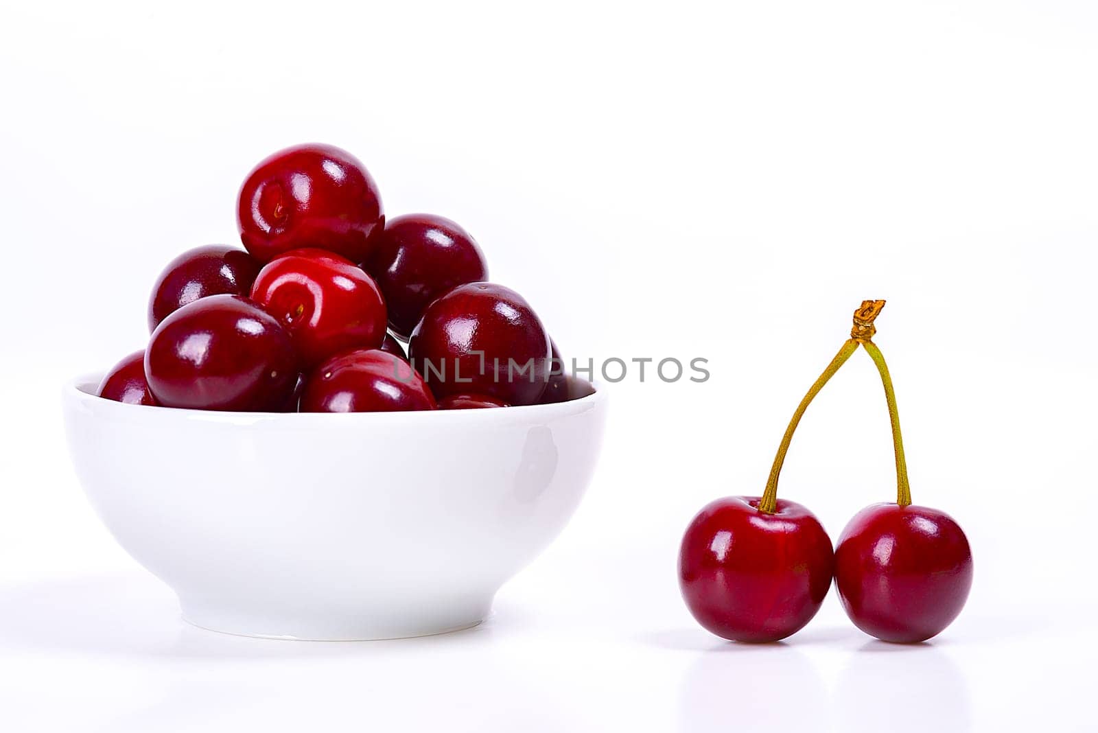 Cherry berries in a white cup on a white background. Isolated. Ripe cherries. Red delicious cherry. Place for advertising, lettering, logo, text, layout, mockup.