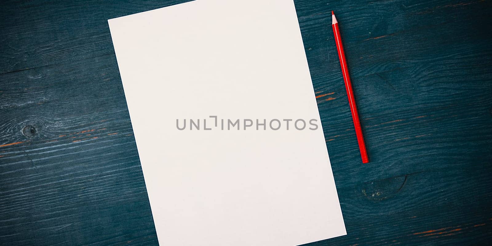 A blank white sheet and pencil for drawing on a wooden background with space for copying and lettering. Layout, mockup free space.